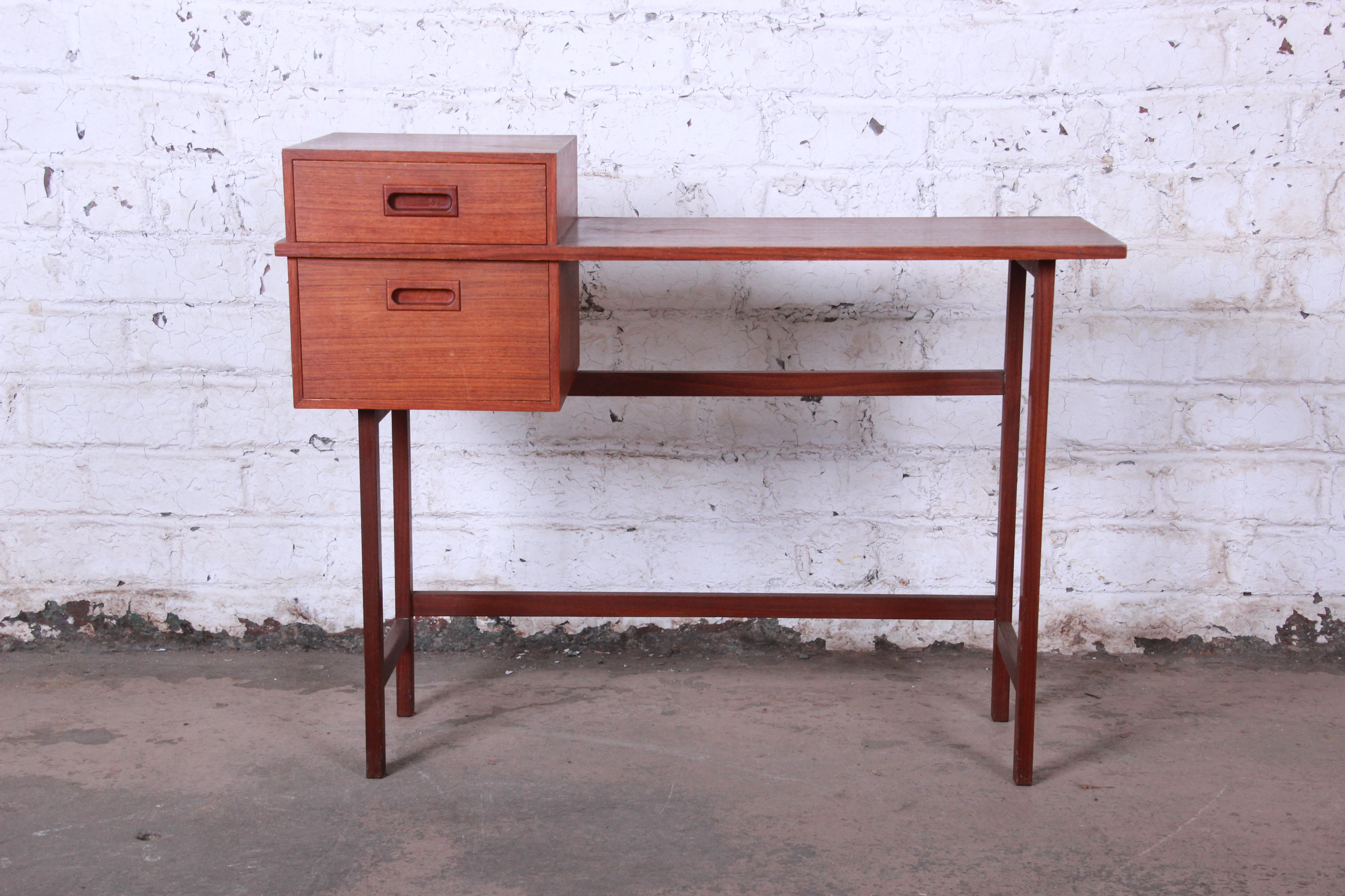 A beautiful and unique Mid-Century Modern vanity desk or console table. The desk was made in Sweden, circa 1950 by Glas & Tra. It features gorgeous teak wood grain, sleek Scandinavian design, and a nice petite size. The desk offers good storage,