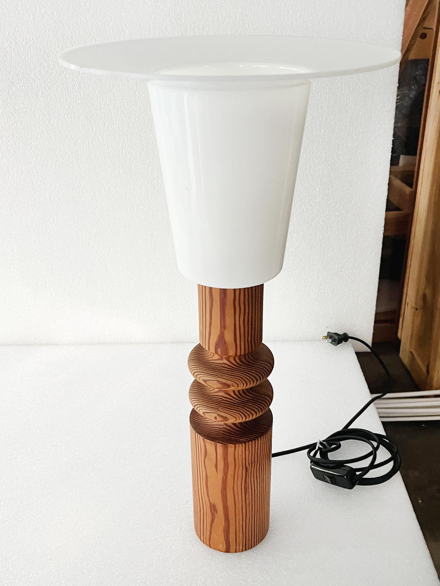 This Swedish Modern table lamp was designed by Uno Kristiansson and made in the 1970s. It consists of a finely turned pinewood base and a white acrylic top diffuser shade. Though seemingly simple in design, the lamp stands out for its excellent