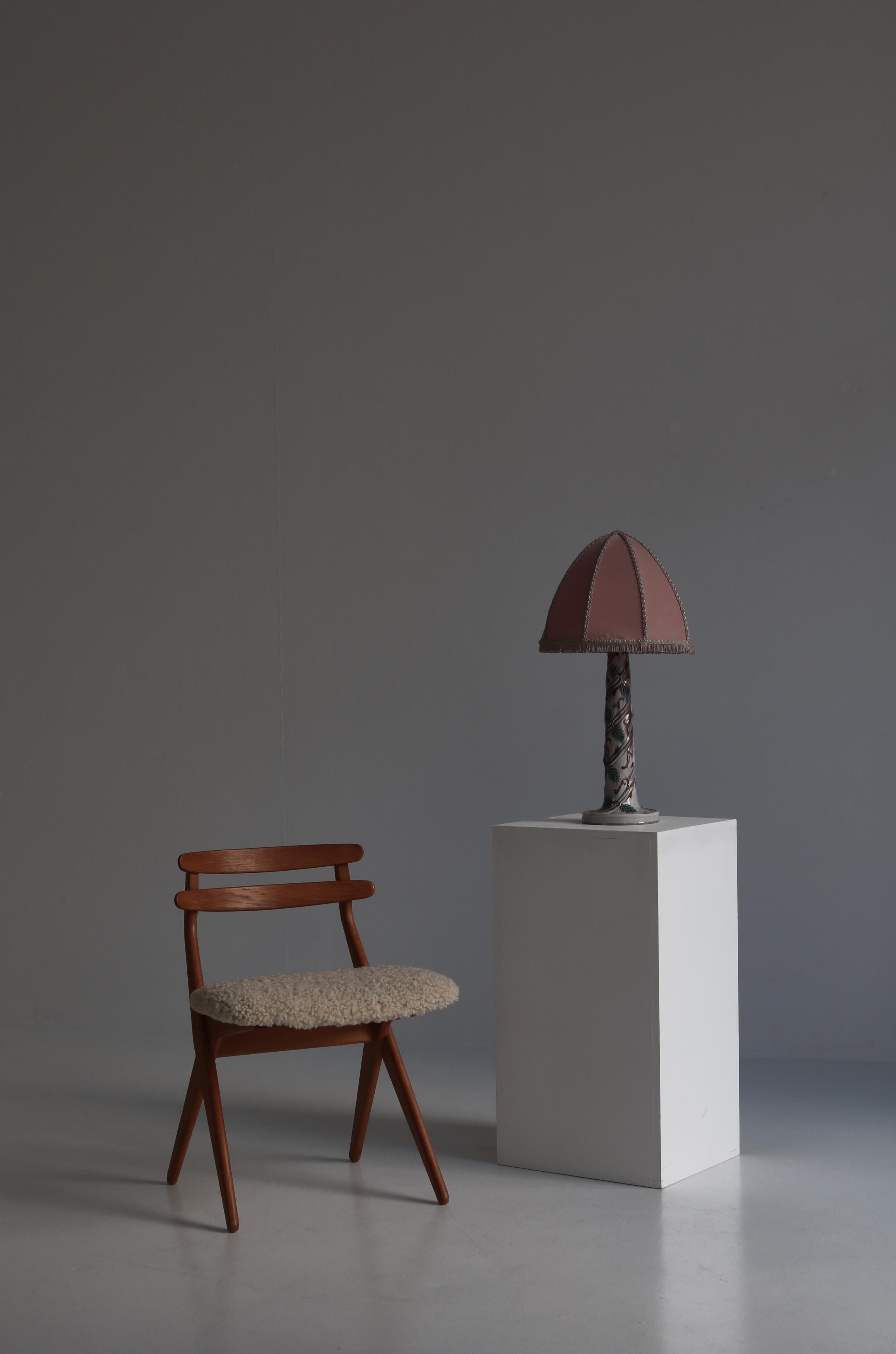 Merveilleuse et unique lampe de table réalisée par l'artiste suédoise Louise Adelborg dans les années 1920. La base de la lampe est fabriquée en porcelaine émaillée avec une décoration de feuillage faite à la main. La lampe est montée avec