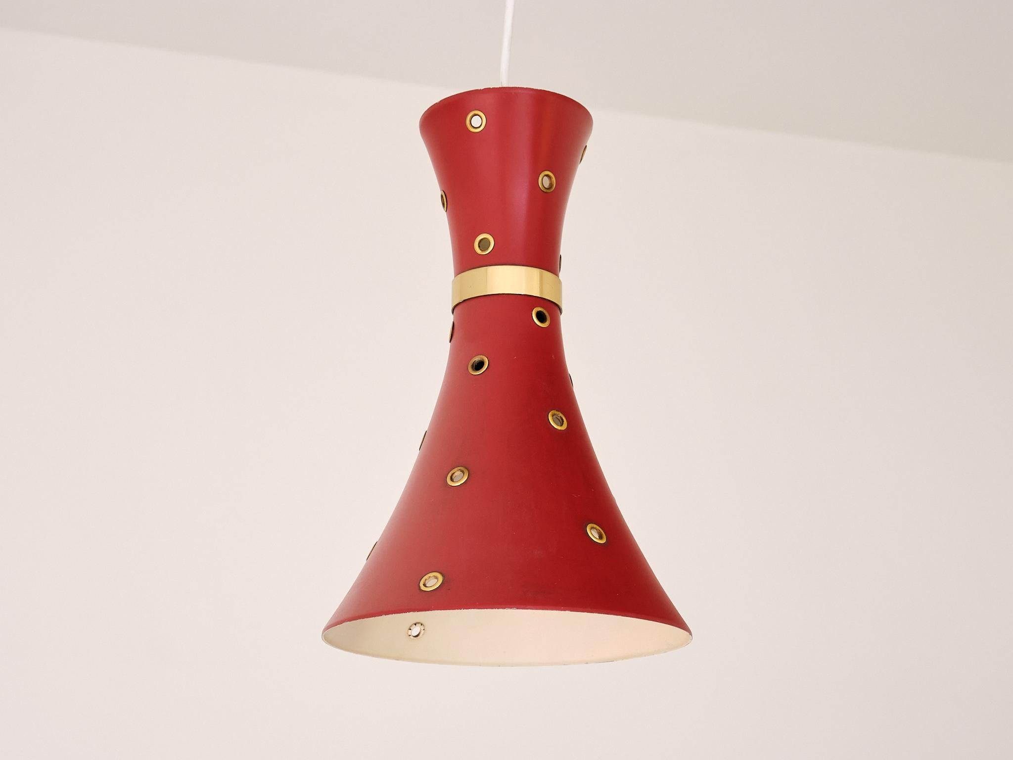 Questa suggestiva lampada a sospensione è stata prodotta in Svezia negli anni Cinquanta. 

Il paralume, caratterizzato da una forma asimmetrica a diabolo, è realizzato in metallo laccato rosso e splendidamente perforato con piccoli fori a puntini.