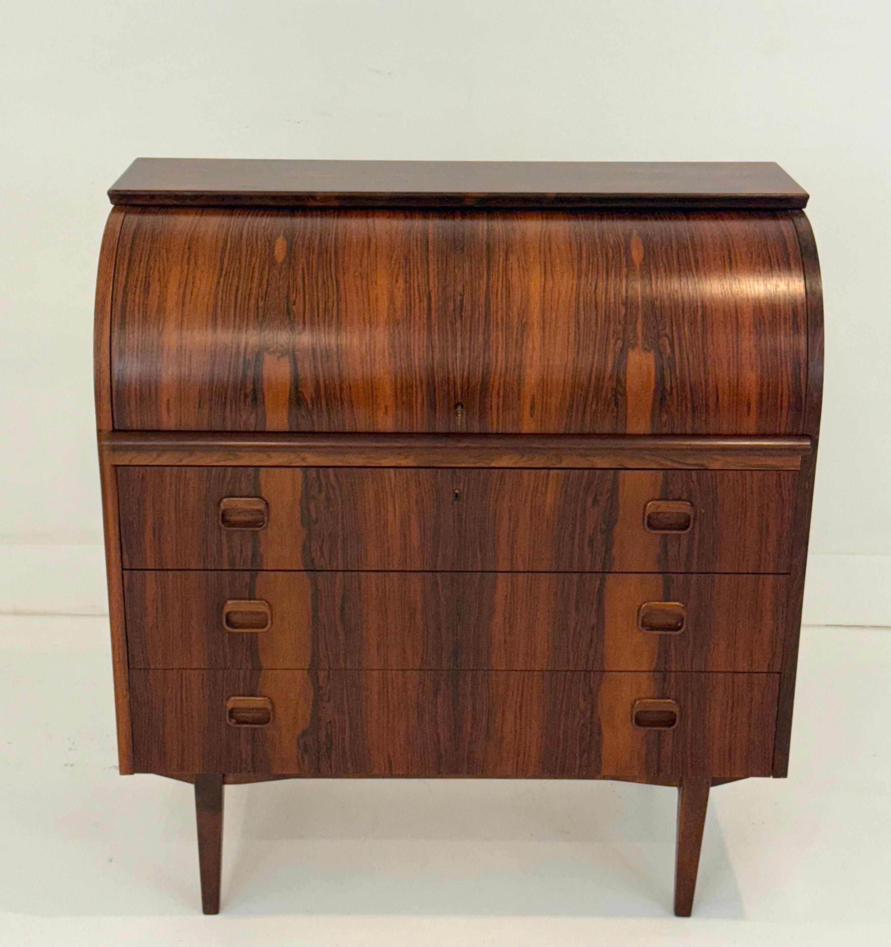 Raffinato esempio di design moderno svedese, questa scrivania a cilindro in legno di palissandro e mogano di Egon Ostergaard per Sven Mobelindustri è stata realizzata in Svezia negli anni Sessanta. Il piano rotante splendidamente curvo mette in