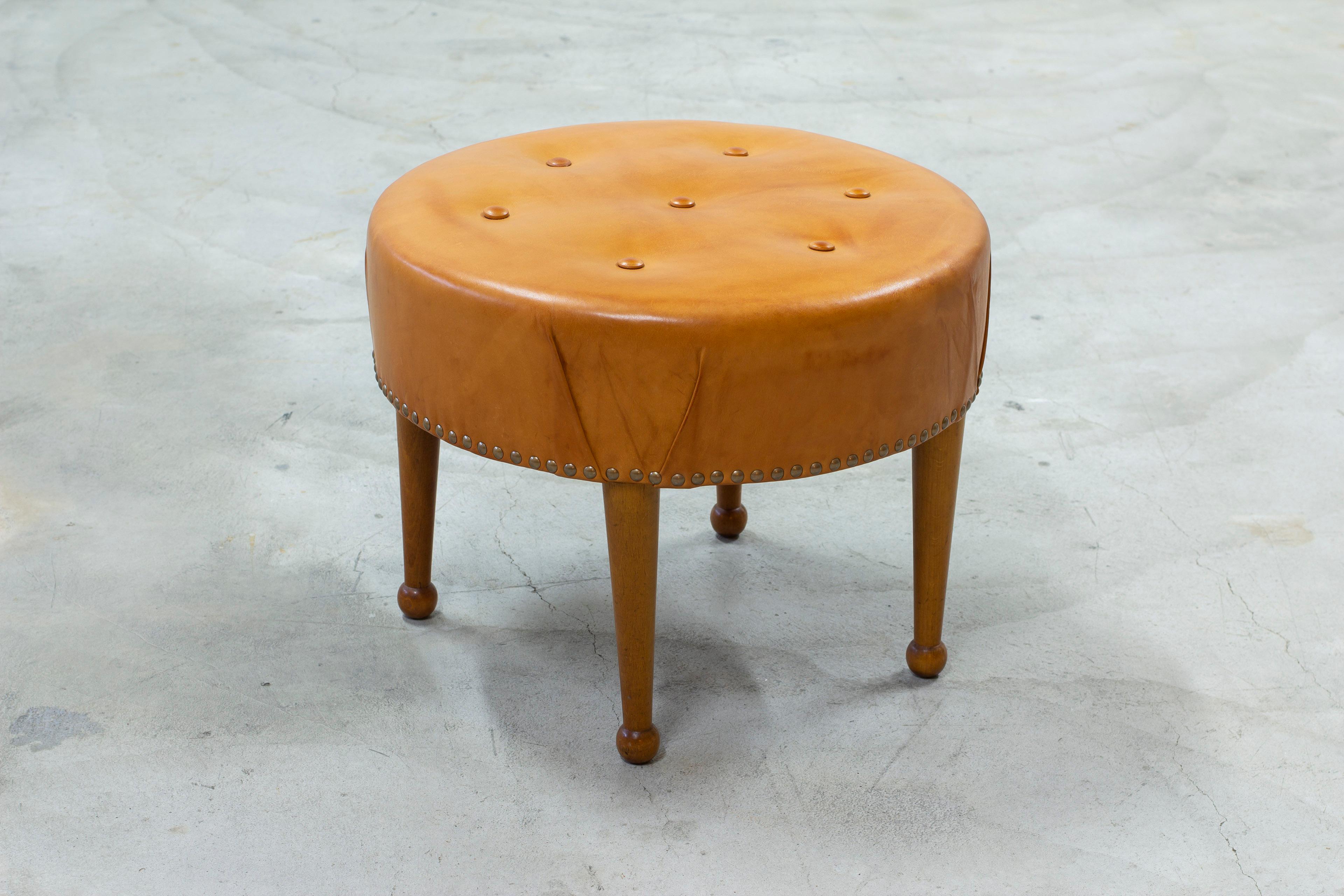 Swedish modern tabouret in the manner of Josef Frank. Cognac leather with beautiful patina and brass nail decor on the rim. Drum stick legs in stained beech. Very good vintage condition with light age related wear and patina.



Designer: