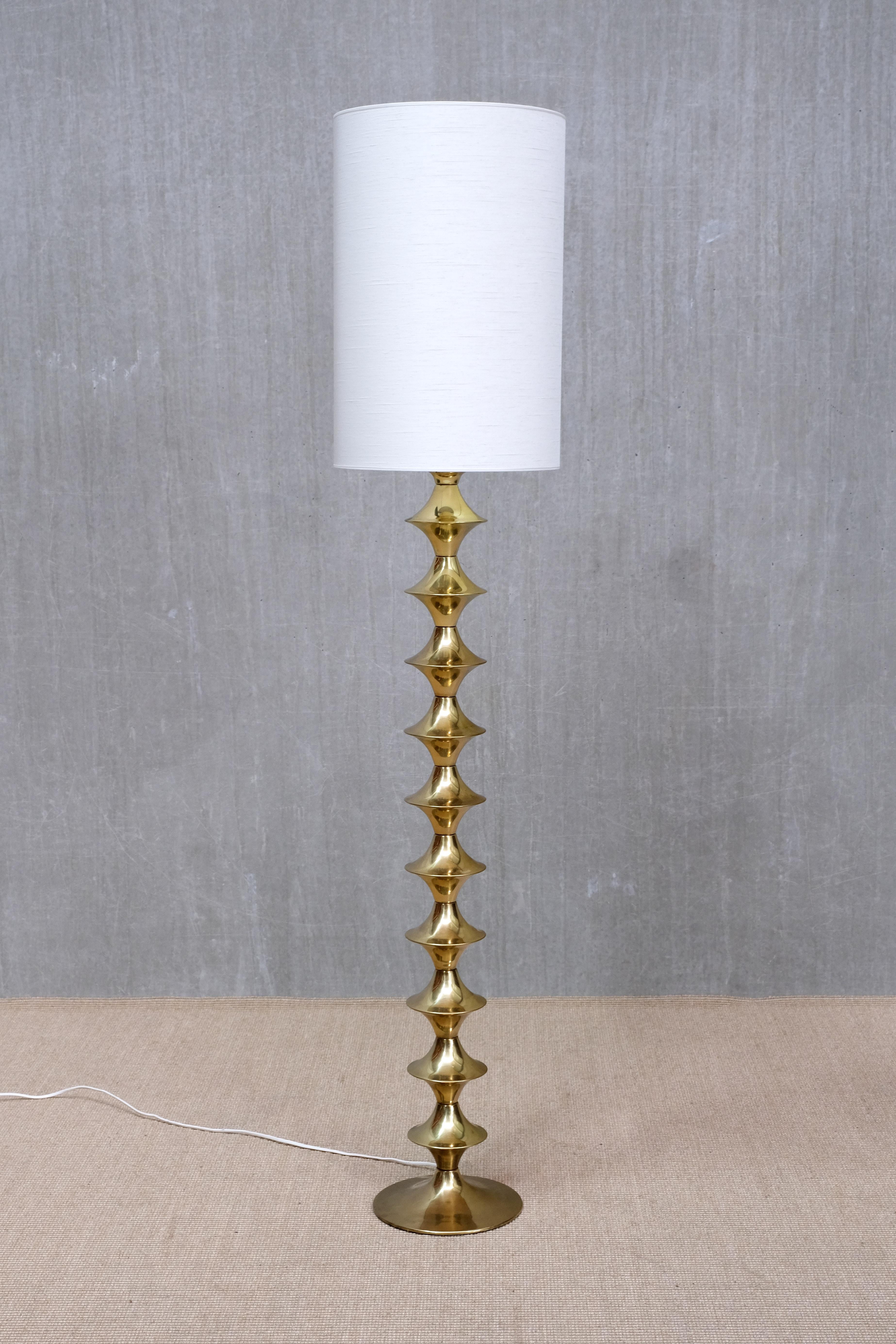 This rare floor lamp was produced by Elit AB in Sweden in the 1960s. It retains its original manufacturer’s label on the underside of the base.

The design features a sculptural stacked column composed of repeating flared, hourglass-shaped brass