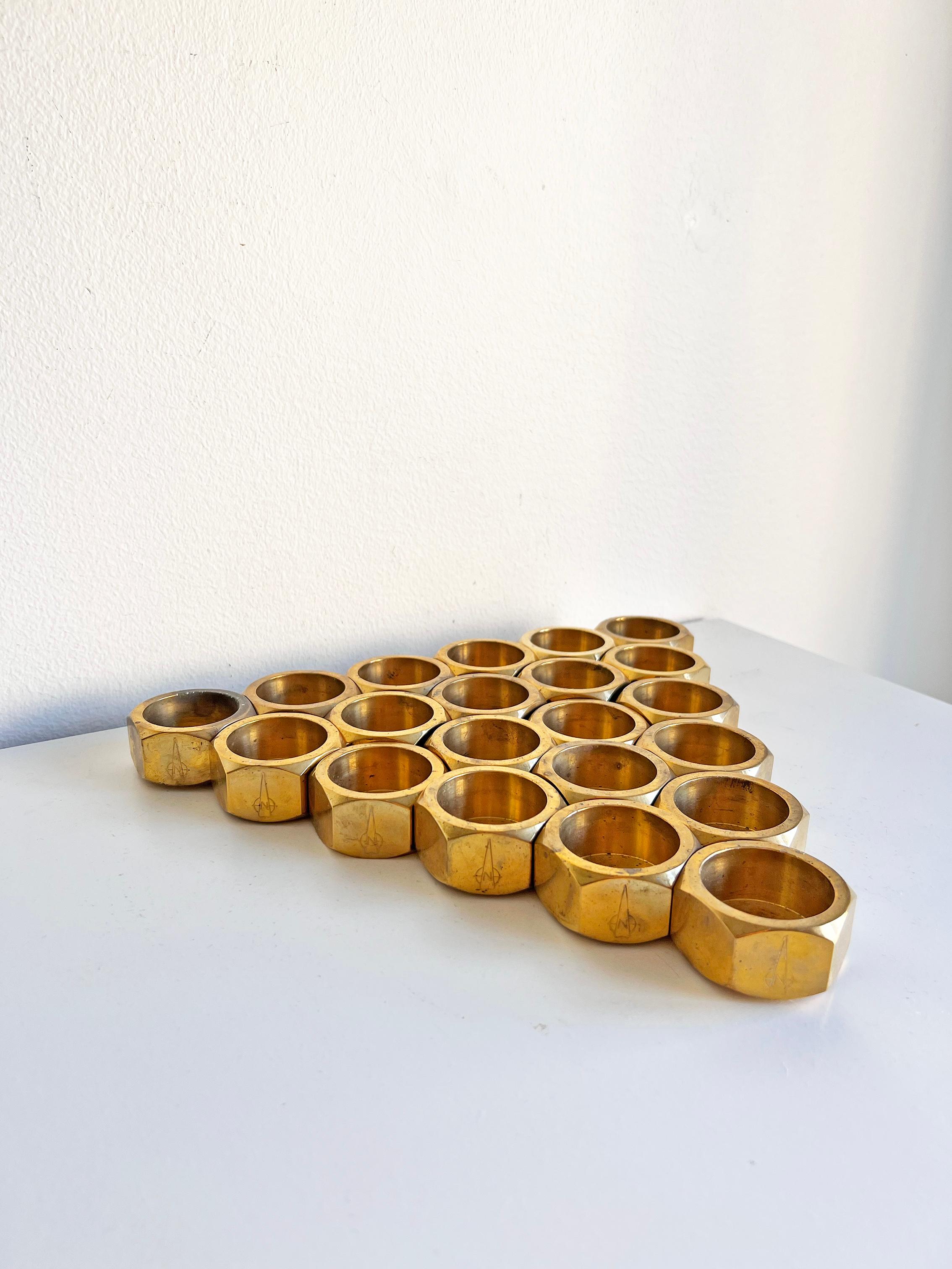 Swedish modern set of 21 candle holders in brass.
Unknown designer and maker, most probably produced In Sweden. 
Marked with an unknown label, as seen on the pictures.
Good vintage condition, wear consistent with age and use. Age-appropriate