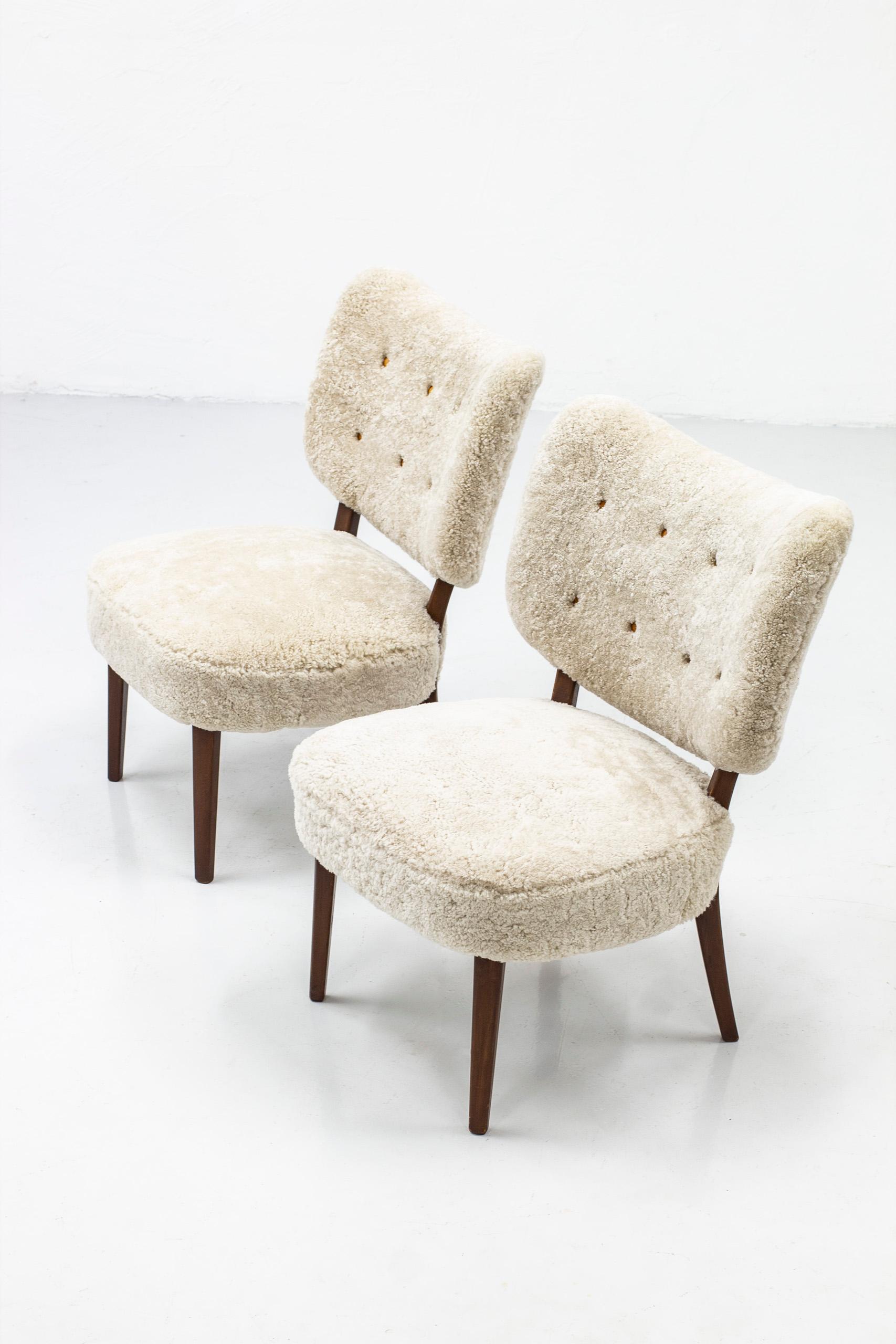 Pair of Swedish modern lounge chairs. Reminiscent to the style of Otto Schulz. Made in Sweden during the 1940-50s. Stained beech wood and new sheep skin fur upholstery with cognac leather buttons. Very good vintage condition. Upholstery is new.