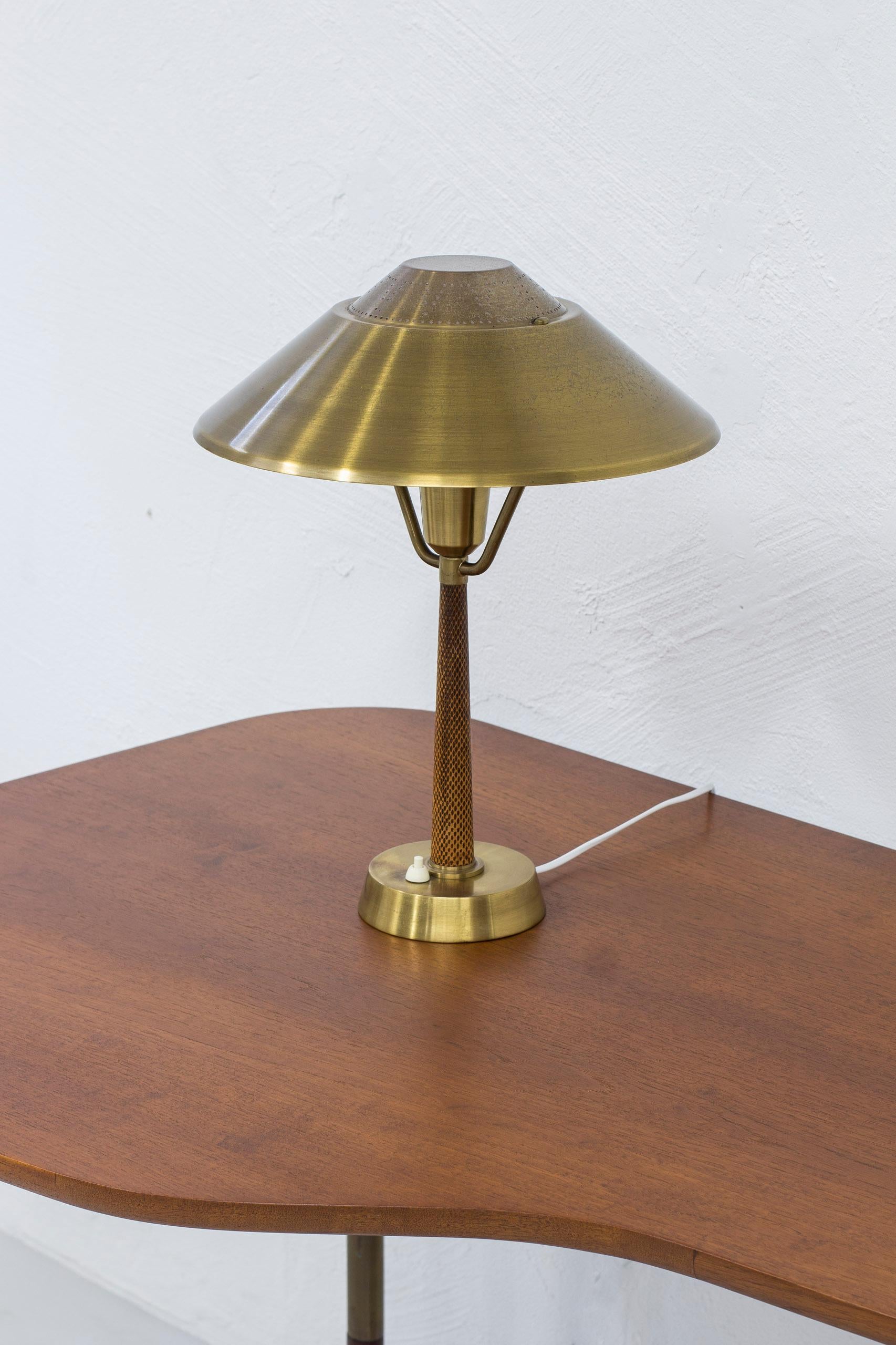 Table lamp produced in Sweden by AB E. Hansson & Co. Made from brass with original snake skinn embossed leather. Lamp shade adjustable in angle. Light switch on the base in working order. Very good vintage condition with light age related wear and
