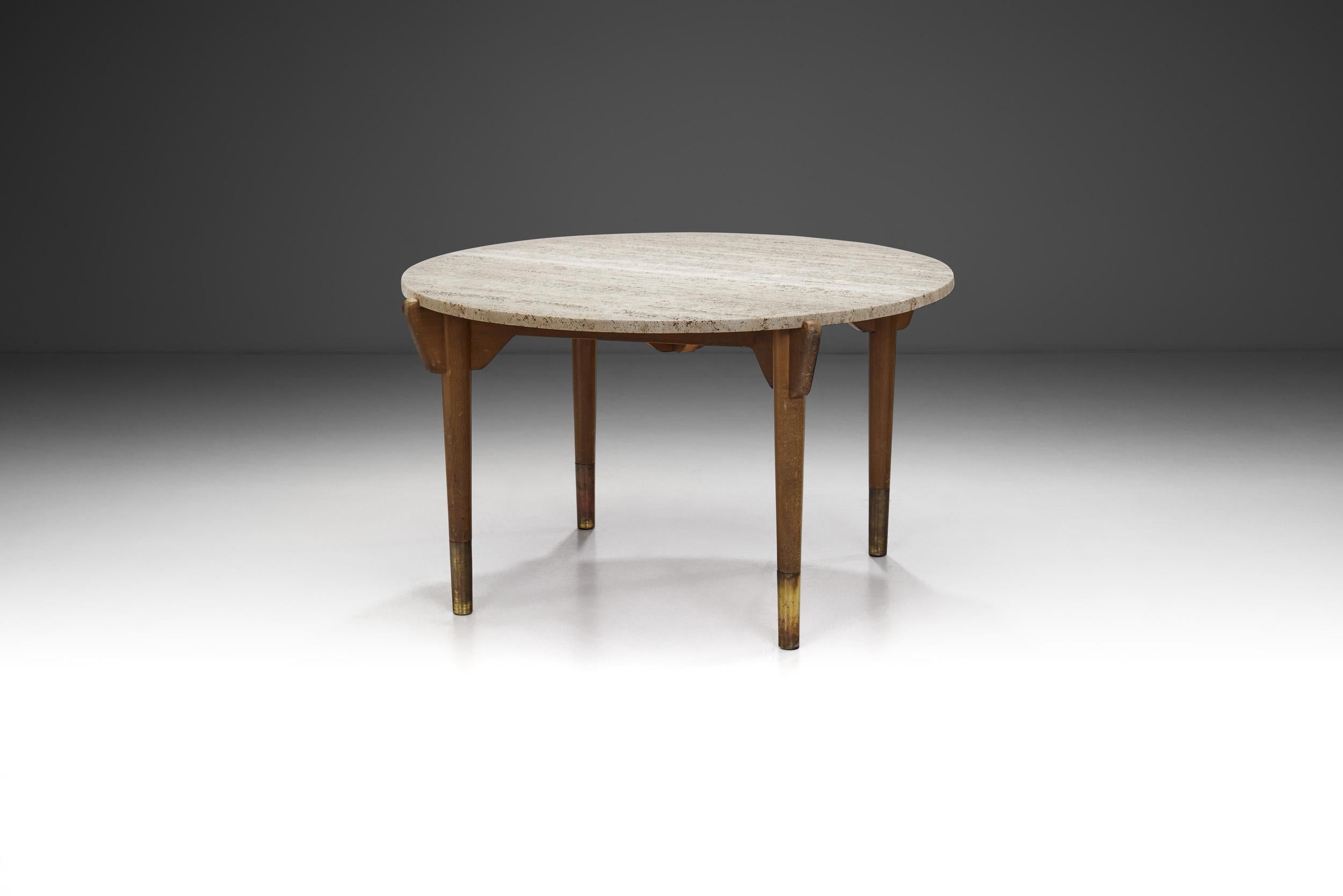 This Swedish Modern 1940s coffee table represents an exquisite blend of functionality, craftsmanship, and aesthetic appeal. Its base, crafted from stained beech, provides a sturdy foundation, while the round table-top in travertine adorned with