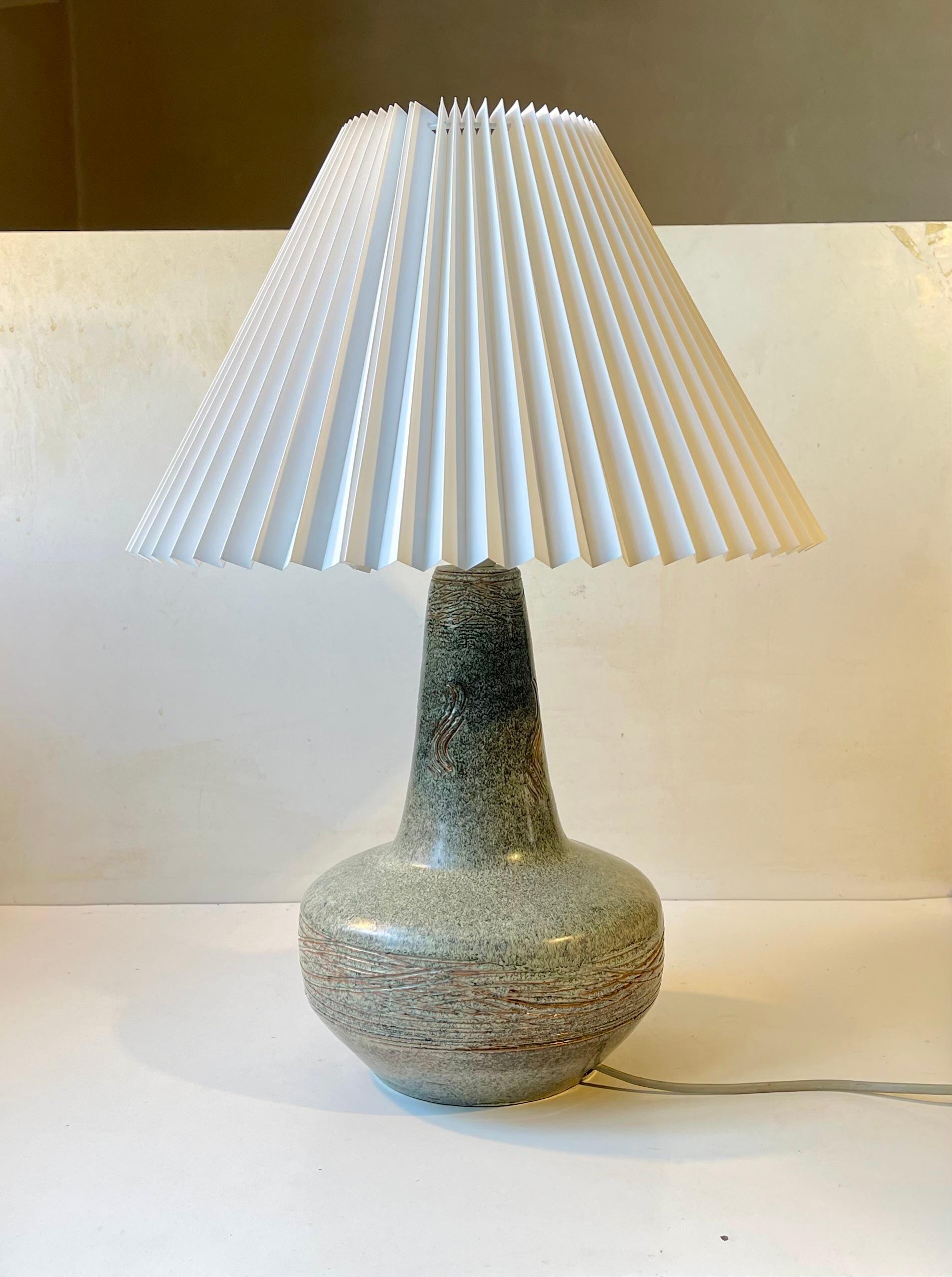 Grande lampe de table en céramique suédoise non identifiée, signée CF ou CE. Il est exécuté dans une glaçure vibrante d'un vert poussiéreux et présente des éléments de la technique italienne du Sgrafitto. Elle est livrée montée en blanc avec un