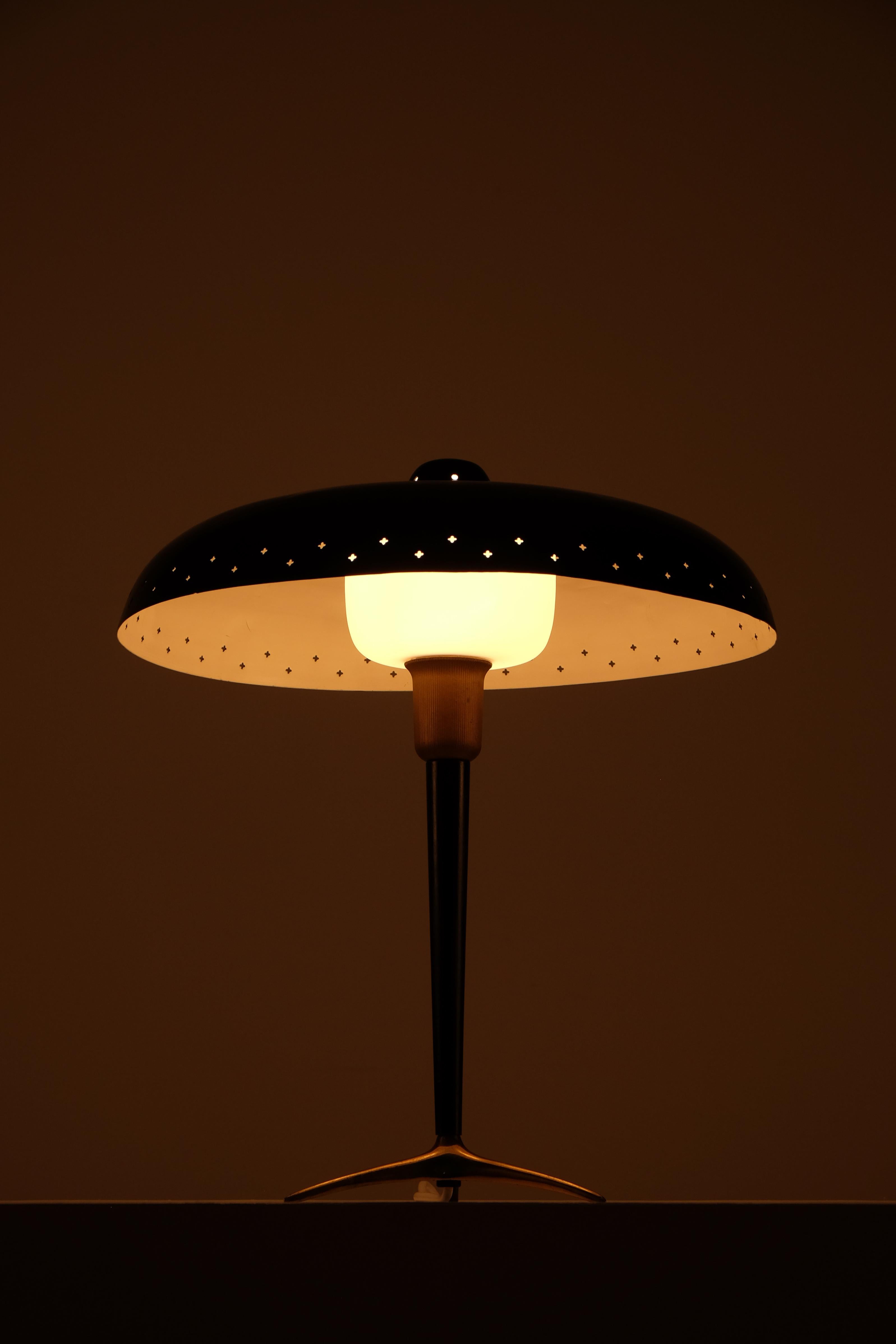 Elégante lampe de table moderne suédoise des années 1950.
La lampe se caractérise par une tige et une base joliment effilées en laiton massif, associées à un abat-jour en métal perforé laqué en noir profond sur l'abat-jour en verre opalin.
Les