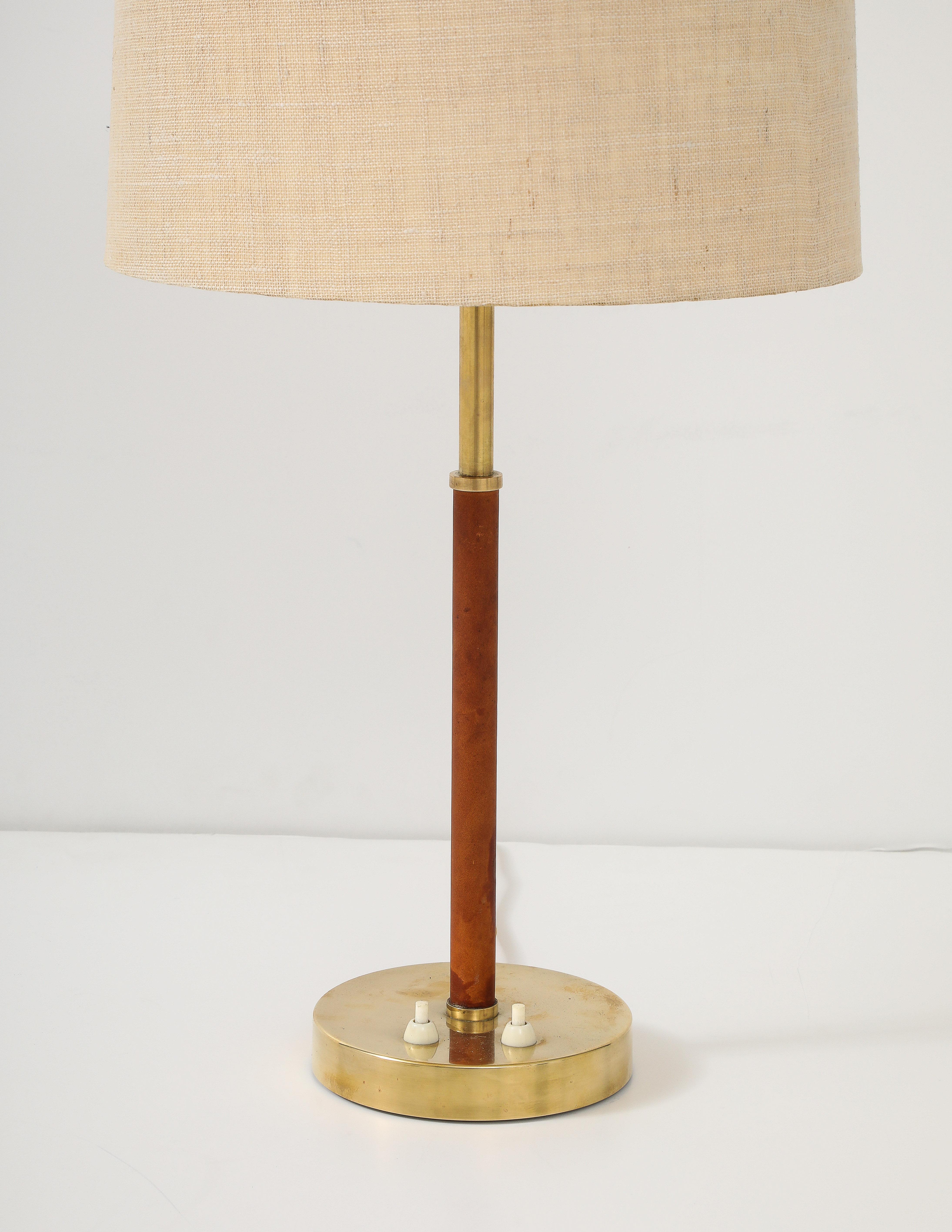 A Swedish Modern brass table lamp with leather wrapped stem, by Bertil Brisborg (1910-1993) & Åke Hultgren, Model # 2043 for Nordiska Kompaniet, Circa 1940s.
Original fabric shade. Two light switches - one for a central uplight, one for three