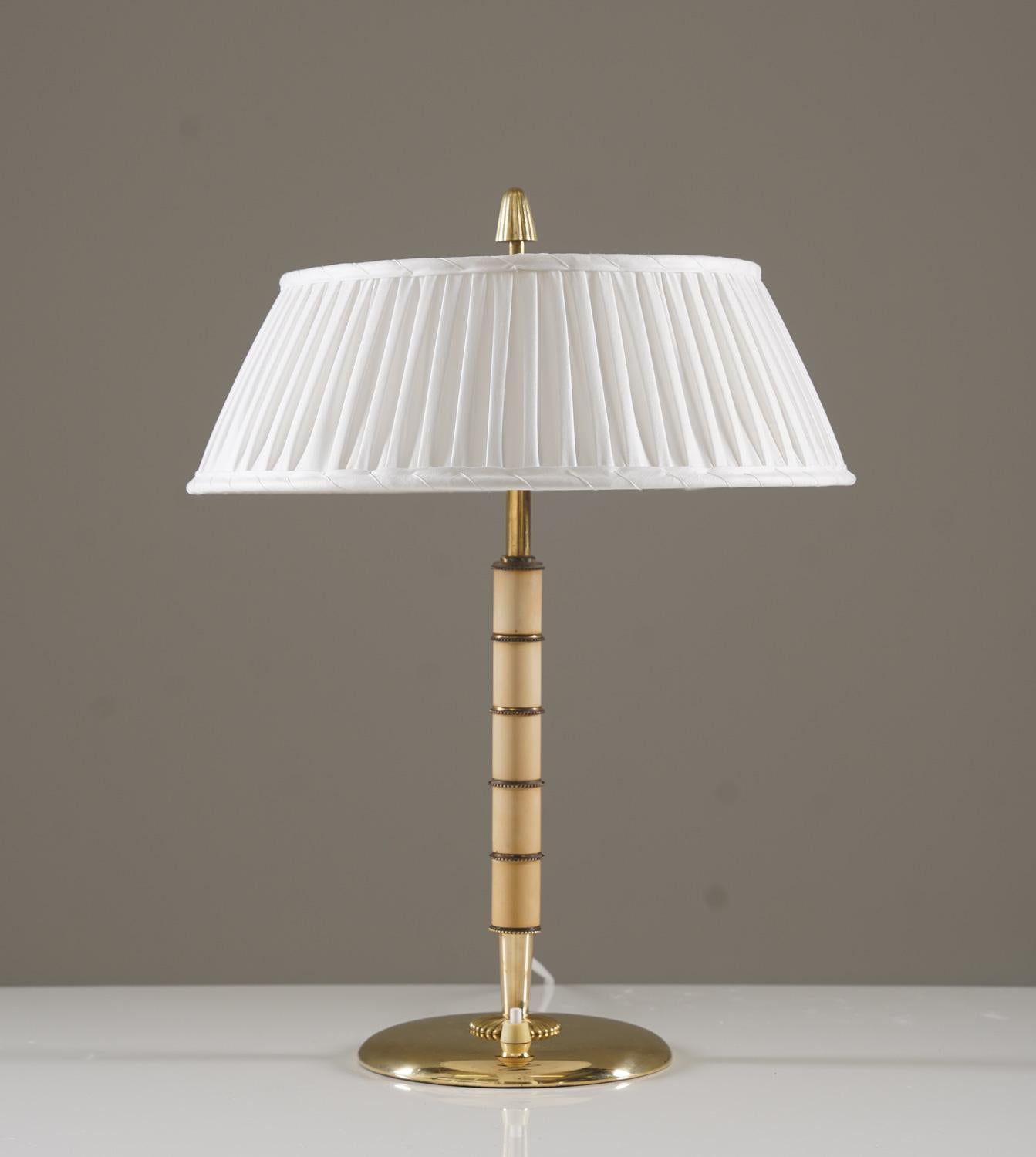 Swedish Modern table lamp by Bertil Brisborg for Nordiska Kompaniet, 1940s.
This elegant table lamp features a sleek brass construction with Bakelite elements, creating a refined contrast between materials. Designed with two light sources, it