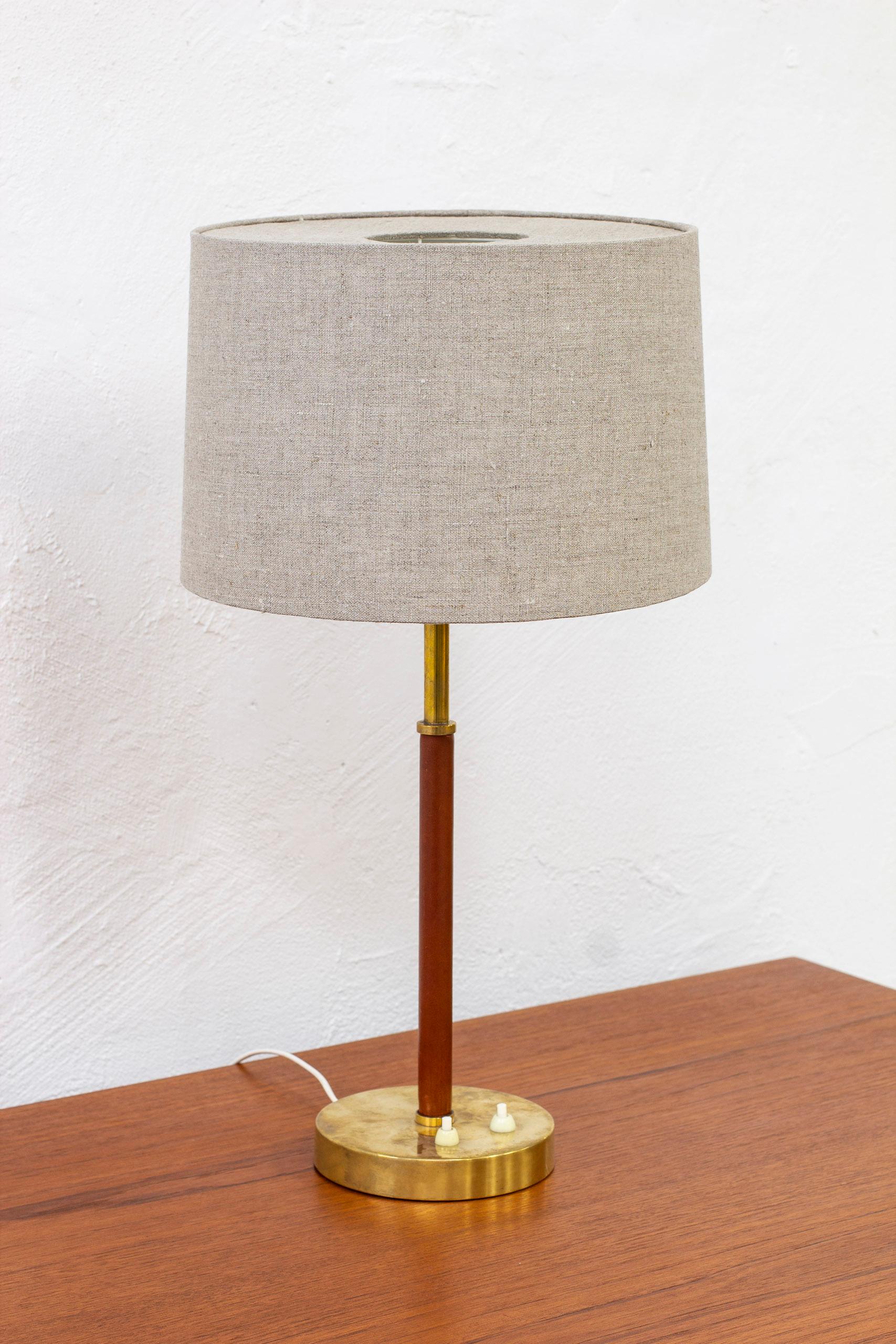 Table lamp model 2043 designed by Bertil Brisborg & Åke Hultgren. Produced in Sweden by Nordiska Kompaniet during the 1950s. Made from brass, white lacquered metal and cognac colored leather. The original lamp shade have been reupholstered in