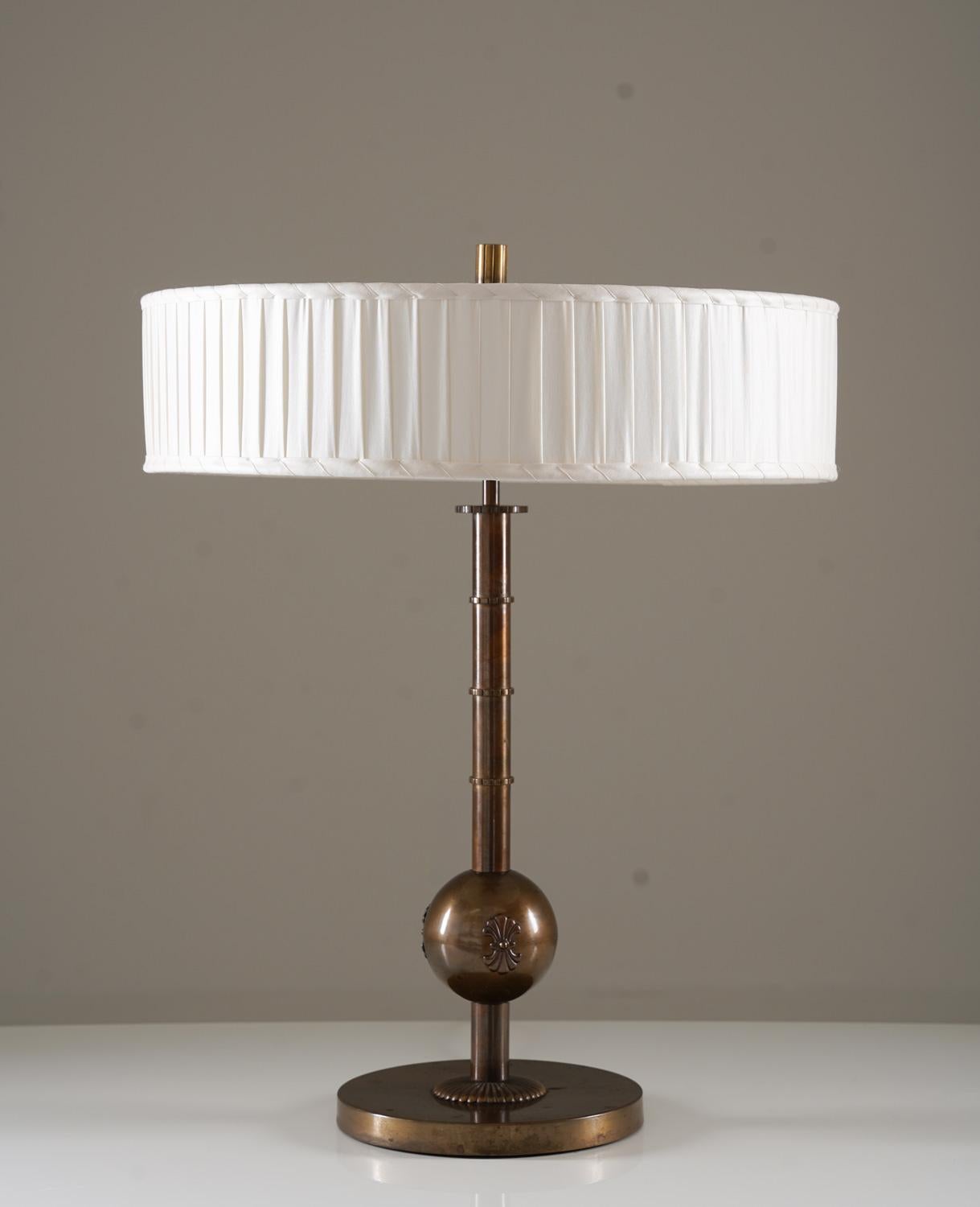 Grande lampe de table fabriquée par Böhlmarks, Suède, années 1930. 
Cette élégante lampe a été fabriquée pendant l'ère moderne suédoise et est de très haute qualité.
Il se compose d'une lourde base en laiton oxydé, supportant une tige ornementée