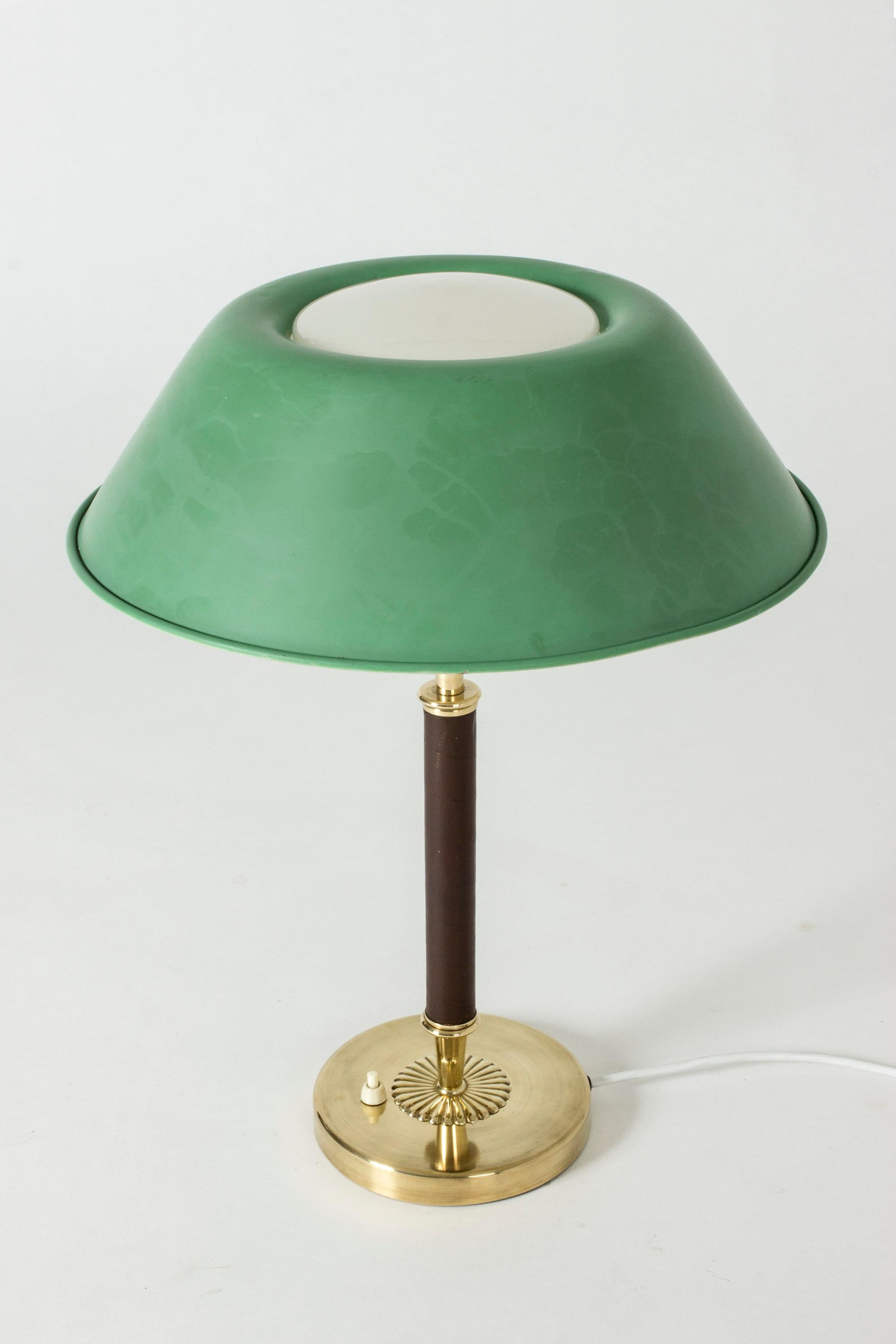 Elegant Swedish midcentury table lamp, with a green lacquered shade. Brass handle wound with brown leather, decorative flower decoration on the base.