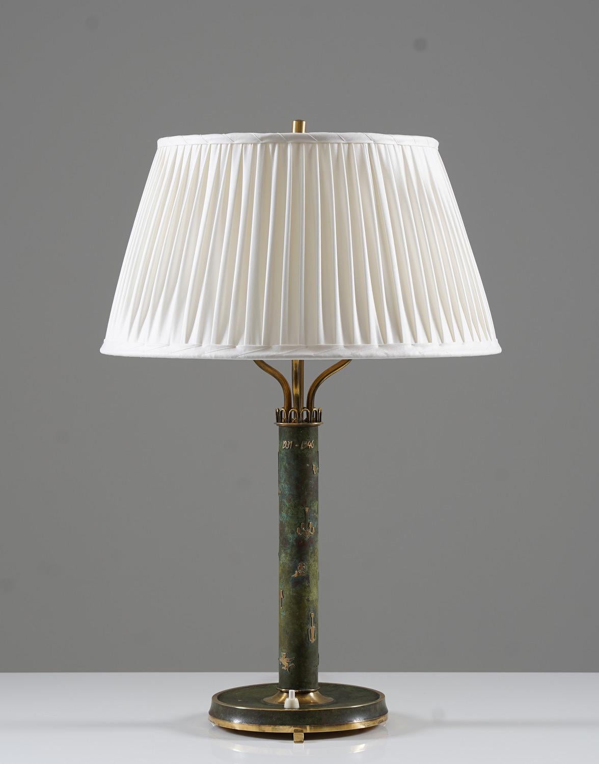 Table lamp manufactured by Liberty, Sweden, 1946. 
This lamp is most likely an in-house production, made in low numbers or even unique. The stem is decorated with different lamp models made by the company and on top it says 