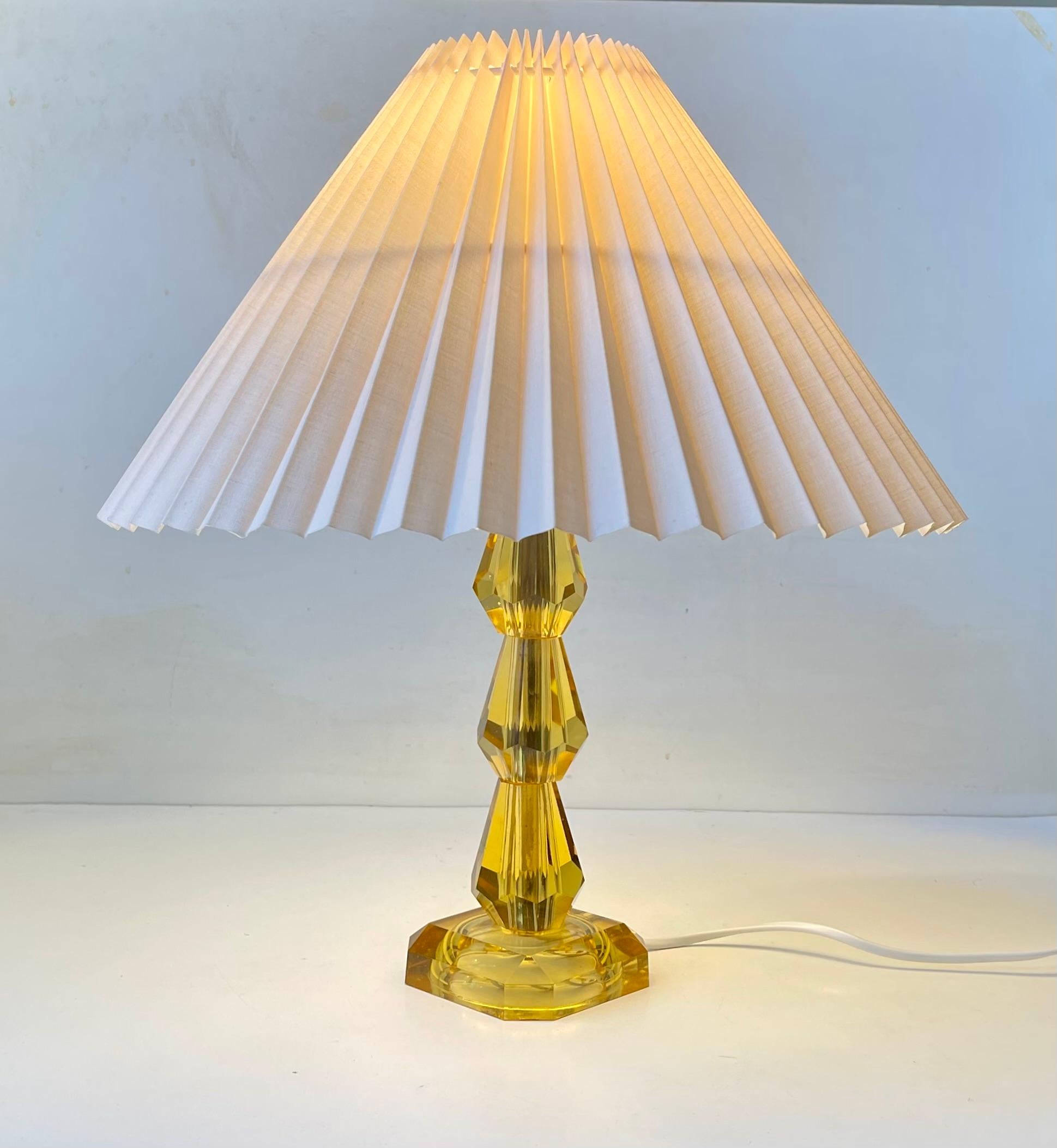 Lampe de table de style Art Déco avec une base et une tige en cristal jaune taillé et facetté. Fabricant/designer suédois non identifié dans le style de Murano et Baccarat. Elle est montée avec un nouvel abat-jour cannelé blanc cassé/tan.  