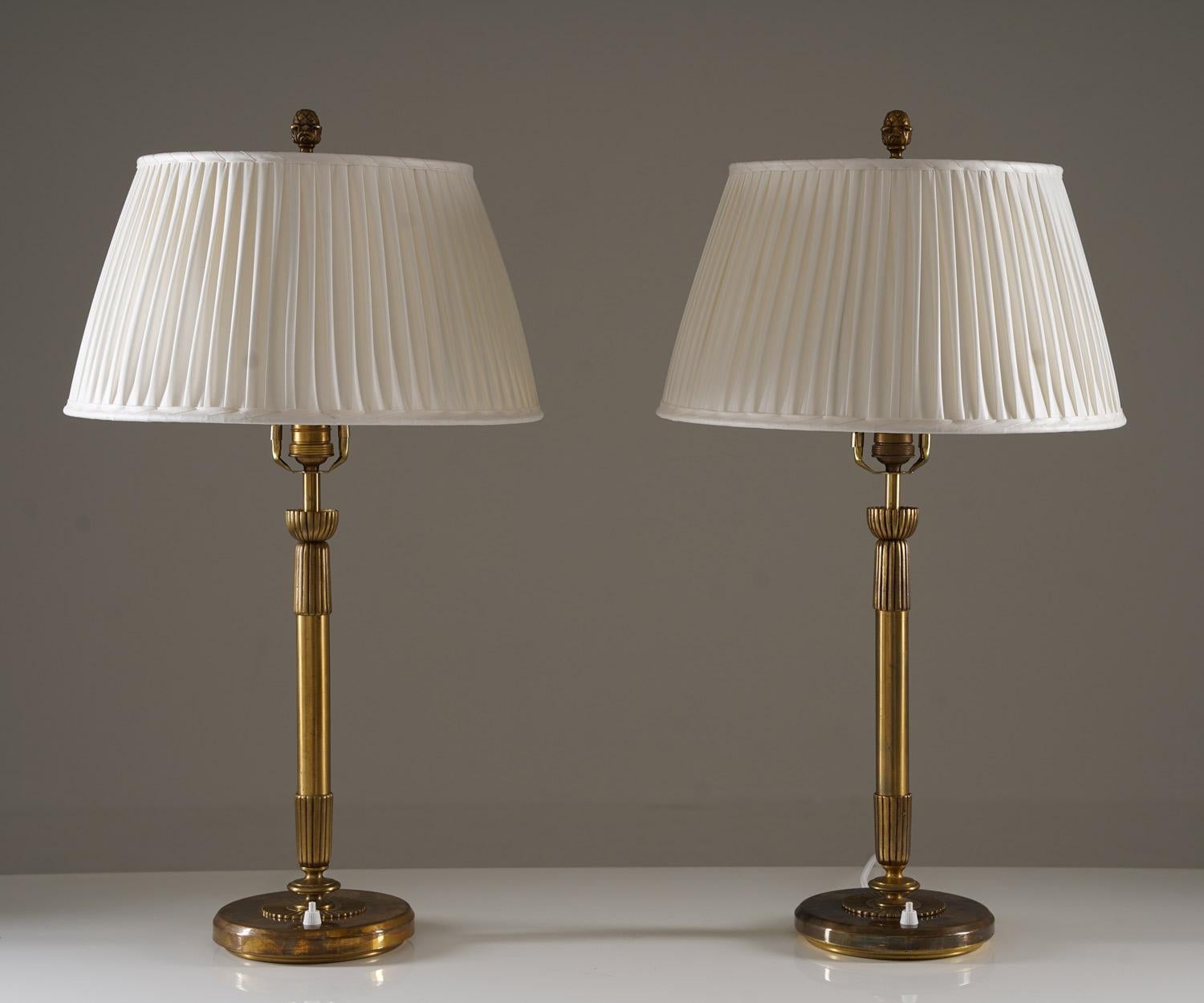 Paire de lampes de table majestueuses fabriquées par Einar Bäckström, Suède, années 1950. 
Les lampes sont en laiton et ont de nouveaux abat-jours en chintz plissés à la main.

État : très bon état. Les abat-jours sont de nouveaux abat-jours en
