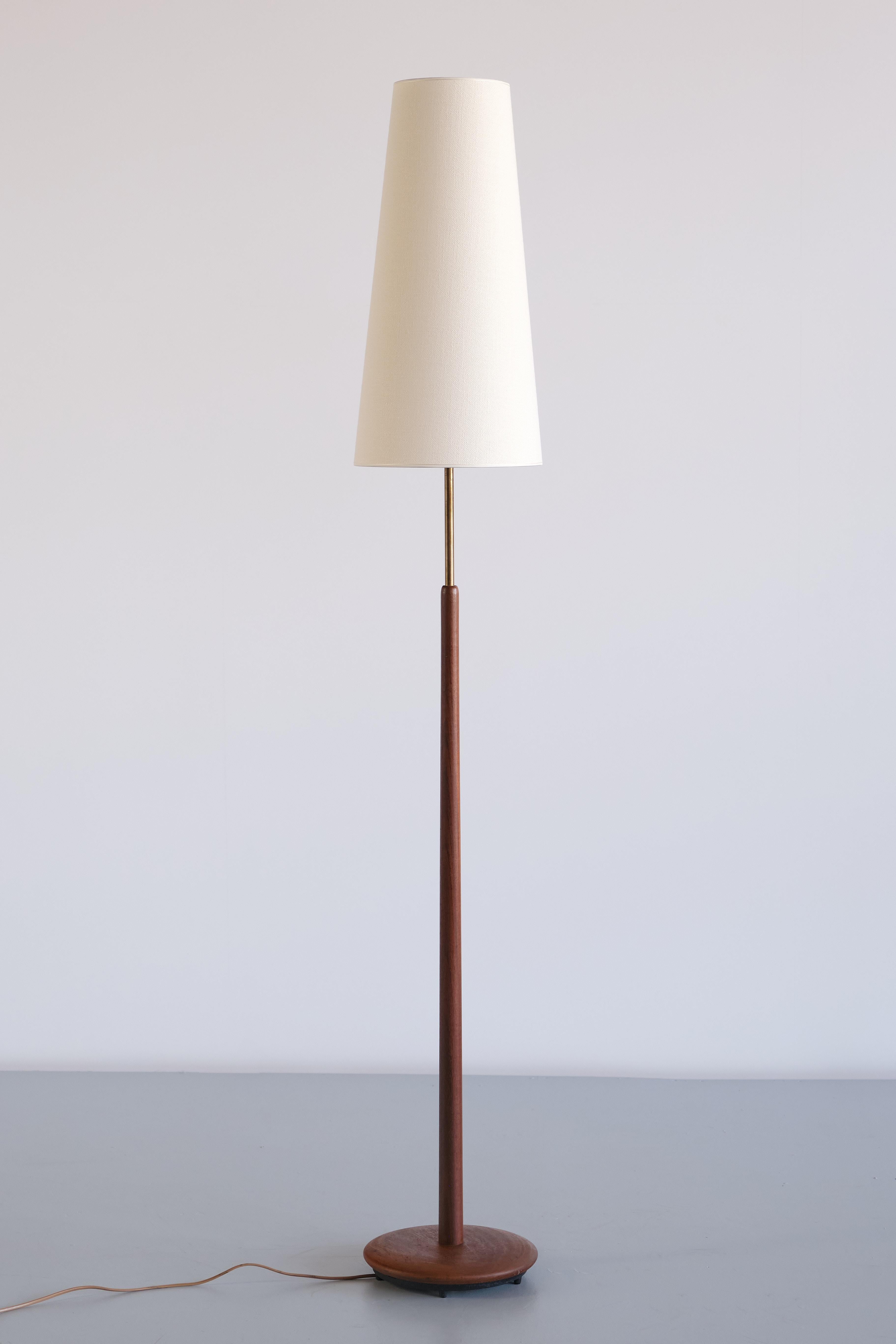 This elegant, tall floor lamp was produced by the Swedish manufacturer NAF Nybro Armatur Fabriken in the 1950s. The design is marked by the central, slightly tapered stem in solid teak wood, resting on a circular teak base. Attached to the top of