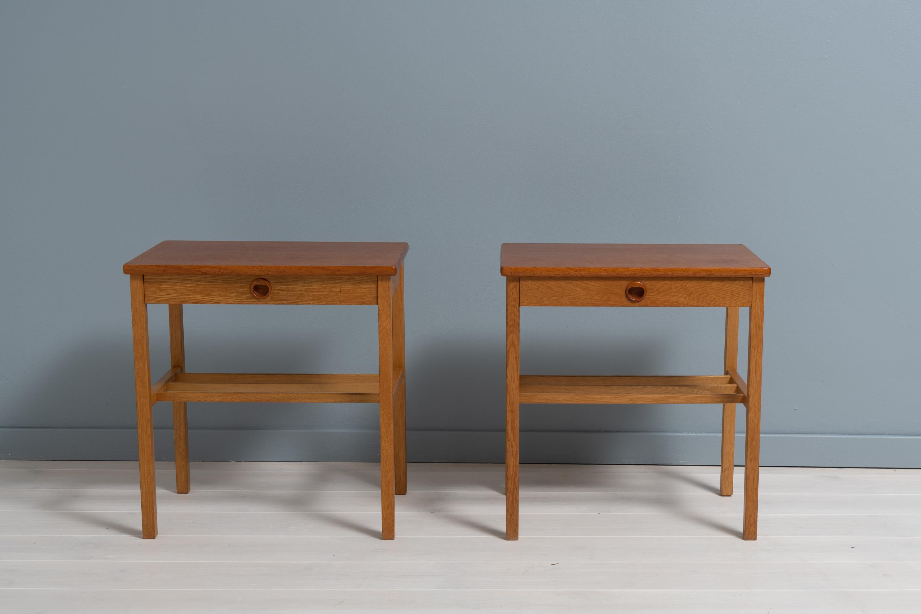 Pair of Scandinavian modern nightstands from Sweden made during the mid 20th century, around 1950. The nightstands are veneered with teak and oak. Good vintage condition consistent with age and use. A pair of nightstands are an easy way to add more