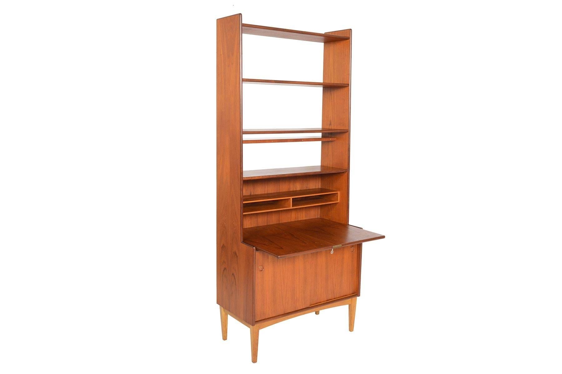 This Swedish modern secretary bookcase by Bräntorps is a versatile storage piece and perfect for any modern home. Bookcase top features three fixed shelves and rests atop of a drop- down case with divided storage. When the case is dropped, a desk is