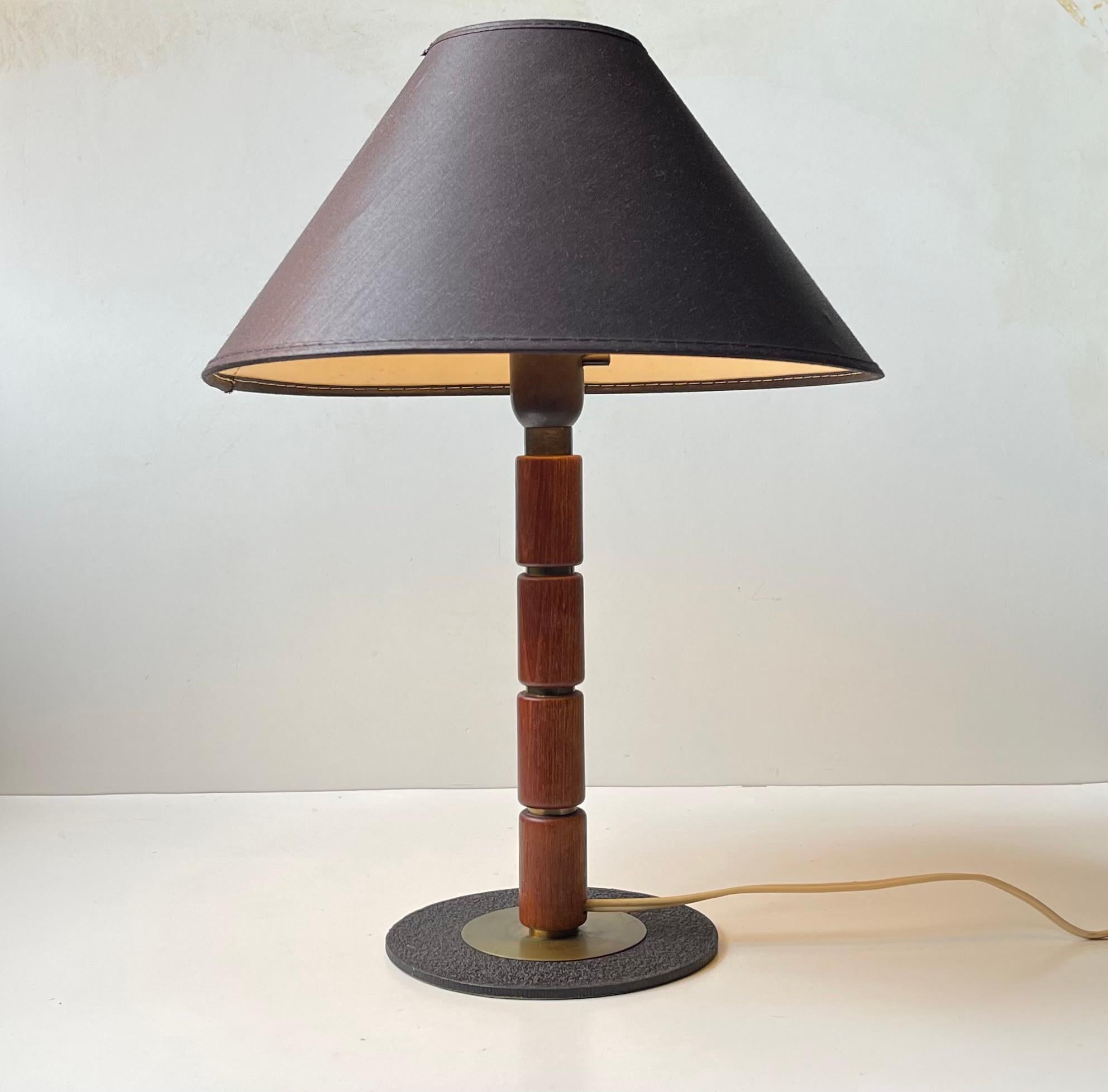Tischleuchte bestehend aus einem Sockel aus Stahl und Messing mit Stange und Akzenten aus massivem Teakholz, hervorgehoben durch Abstandshalter aus Messing. Inklusive schwarzem Vintage-Stoffschirm. Er wurde in den 1960er Jahren anonym in Schweden