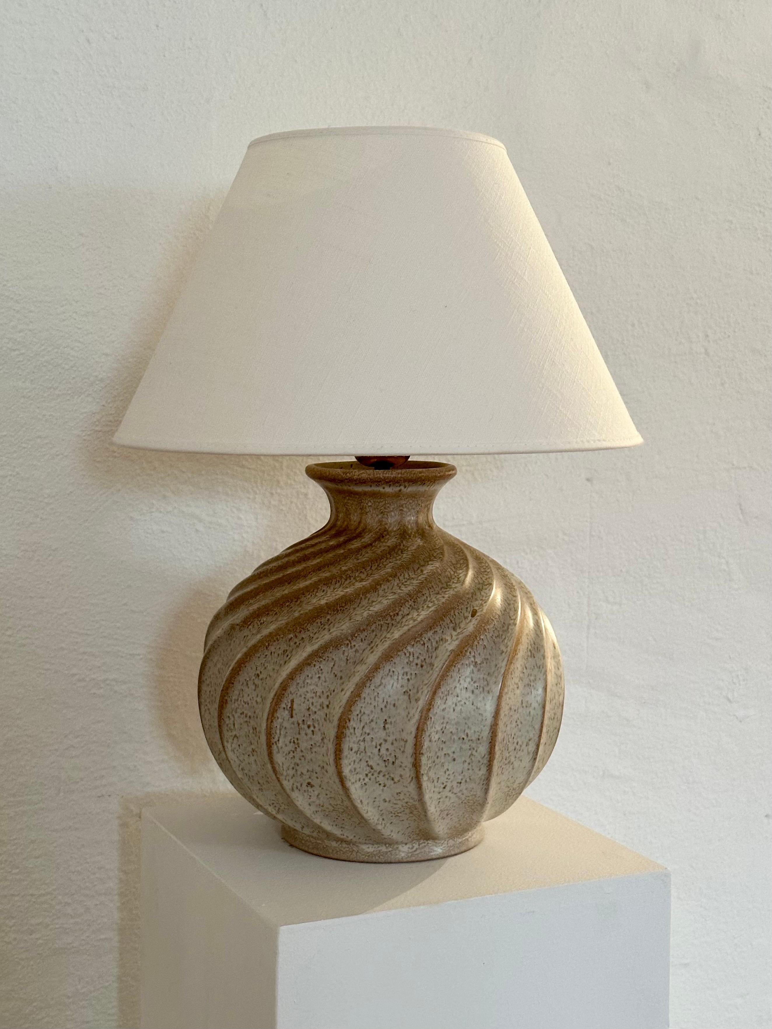 Large table lamp designed by Ewald Dahlskog for Bo Fajans, Sweden, 1930s or early 1940s. This piece is originally a vase of the model D 171 turned lamp. The ceramic base is spherical with twisted channels running down the sides and topped with a