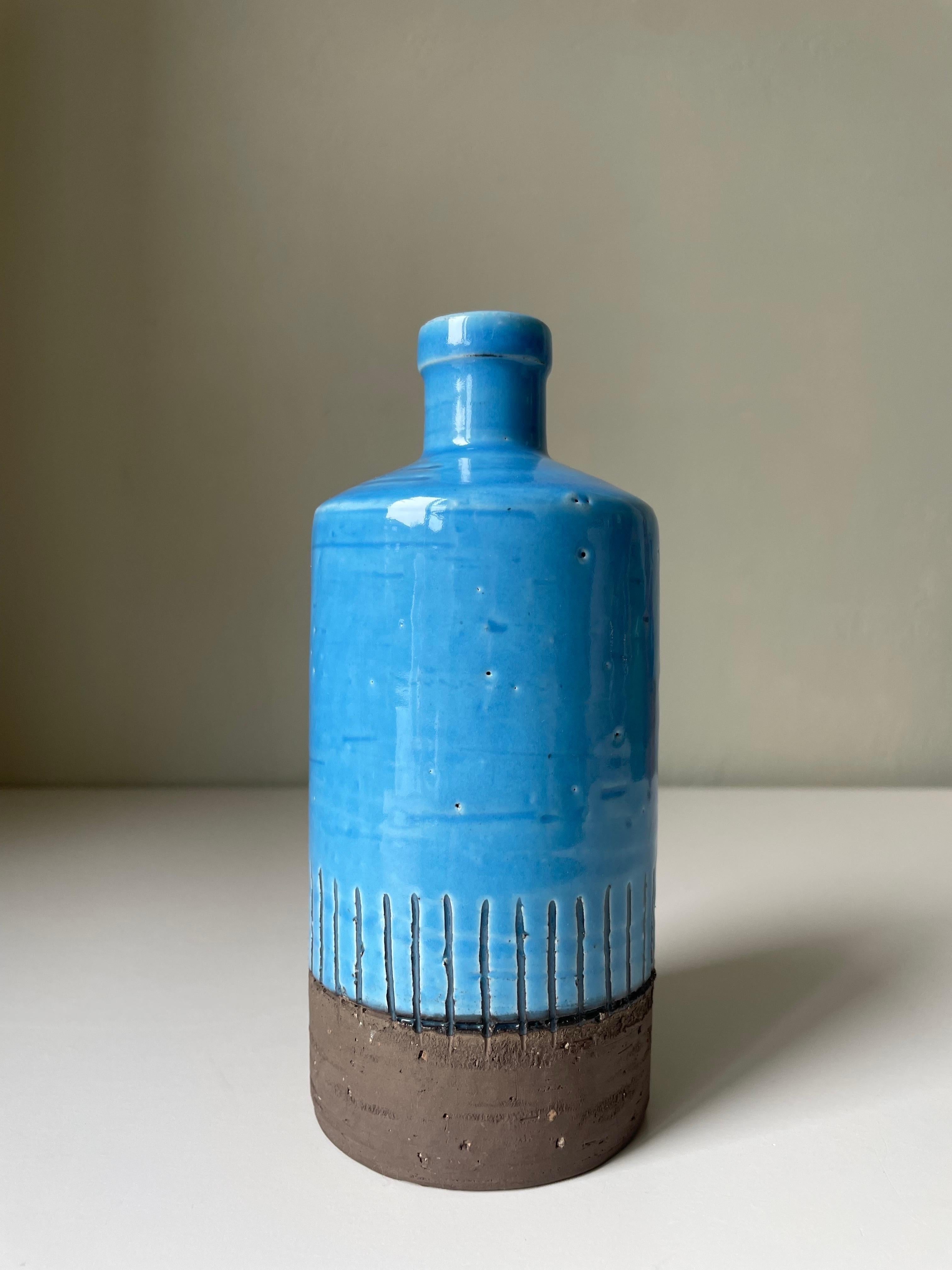 Handmade bottle shaped Swedish midcentury modern chamotte vase with bright blue turquoise glaze. Slender neck and cylinder shaped body. Bottom part left raw and unglazed and right above are handcarved relief lines toward the shiny blue glaze.