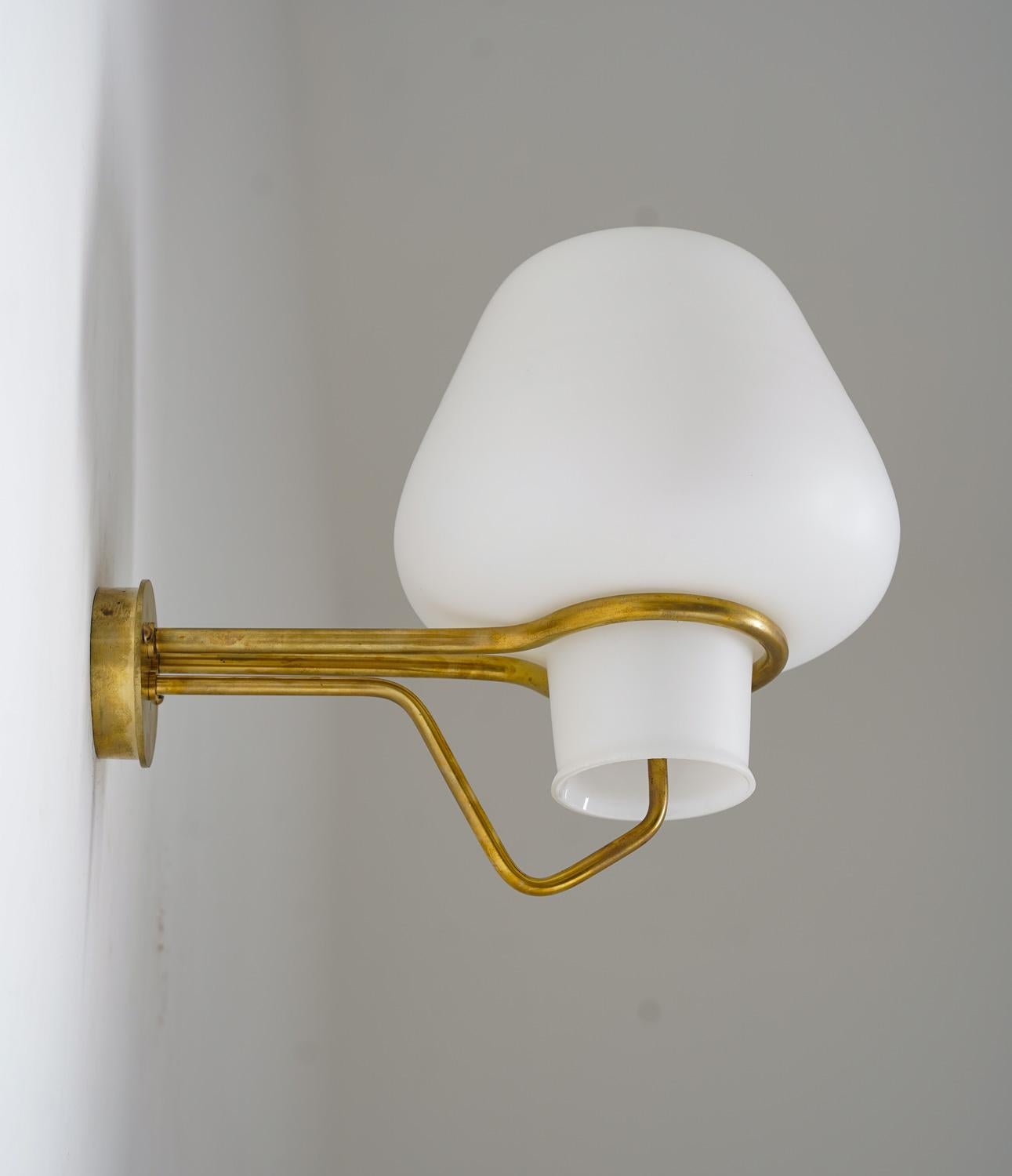Large wall lamps by Gunnar Asplund for ASEA, 1950s. 
These lamps feature a large frosted opaline glass shade, resting on a frame of brass.

Condition: Very good, the brass has been polished by the former owner.