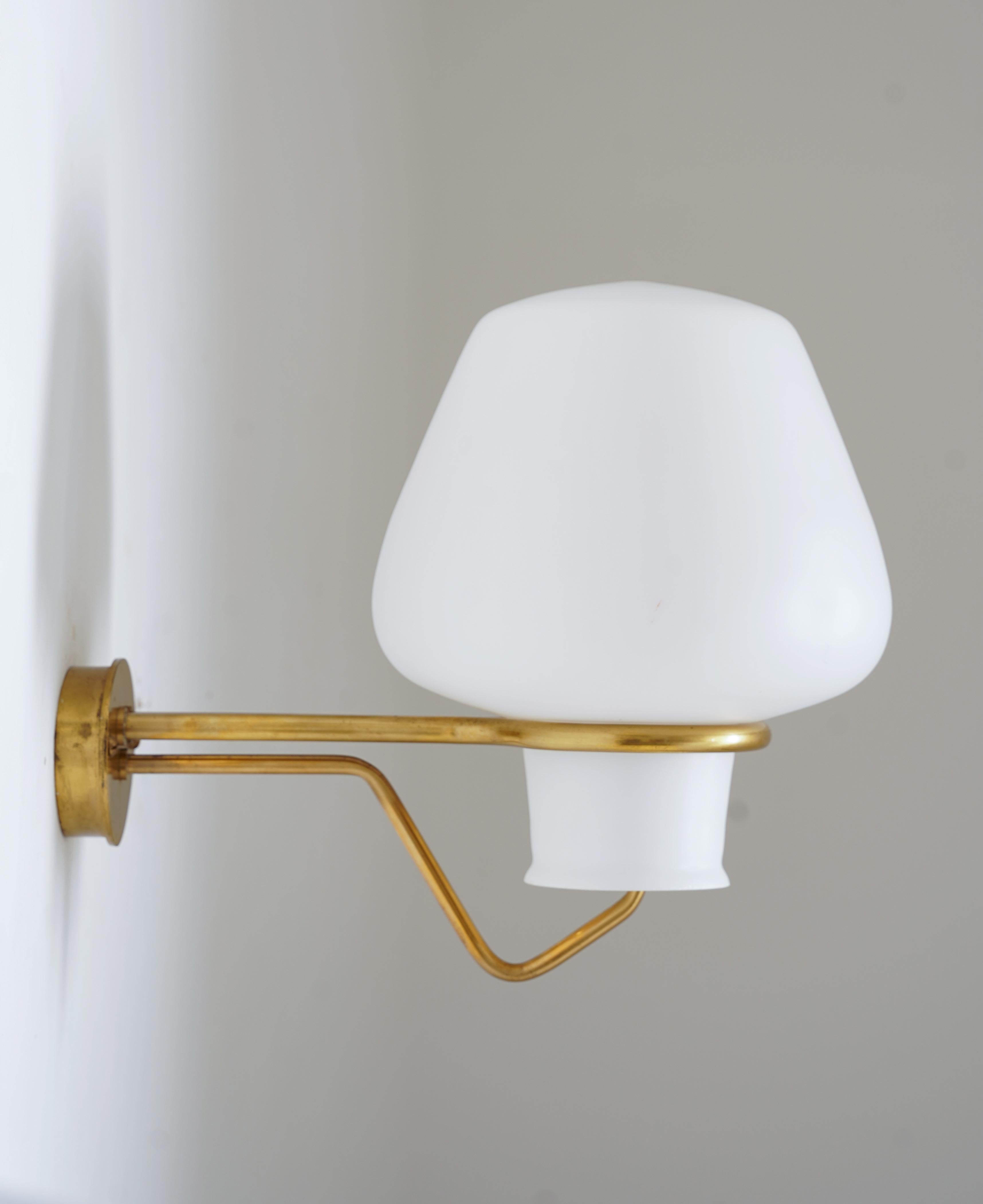 Large wall lamps by Gunnar Asplund for ASEA, 1950s.
These lamps feature a large frosted opaline glass shade, resting on a frame of brass.

Condition: Very good original condition with some scratches and spots on the brass. A chip on one of the