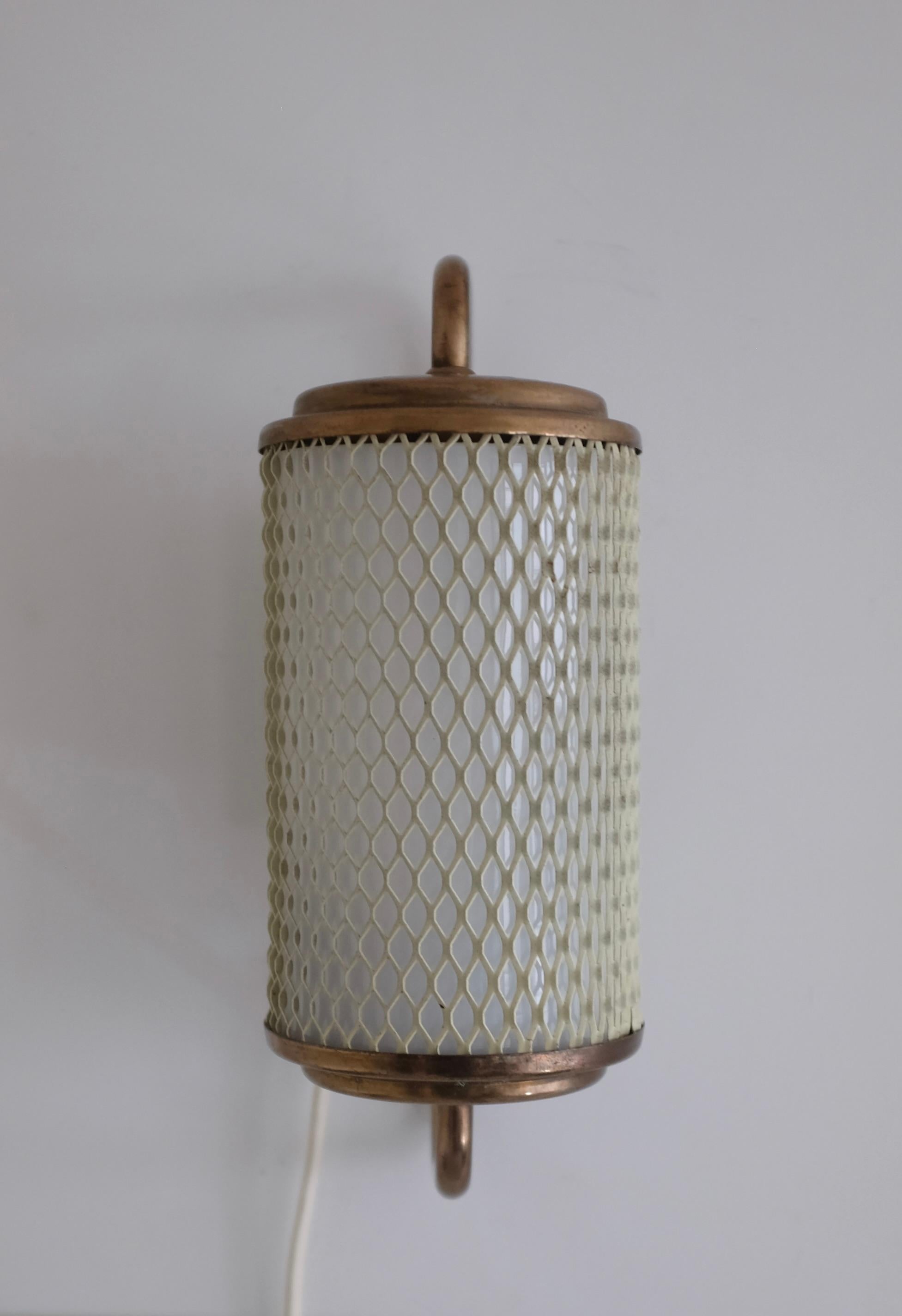 Charming Swedish Modern Wall lamp made out of expanded metal and brass. The metal creates a mesh design in off white with an internal white glass lantern. Can be mounted vertical or horizontal on the wall. From the 1940/50s by an unknown designer