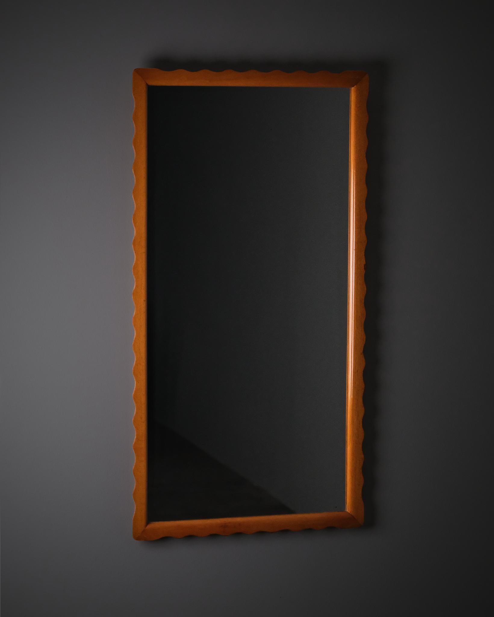 Elegant wall mirror produced by Fröseke during the 1940s, exemplifying the refined simplicity of Swedish Modern design. The frame is crafted in beech with subtly undulating, wave-shaped edges that add a tactile rhythm to its clean rectangular