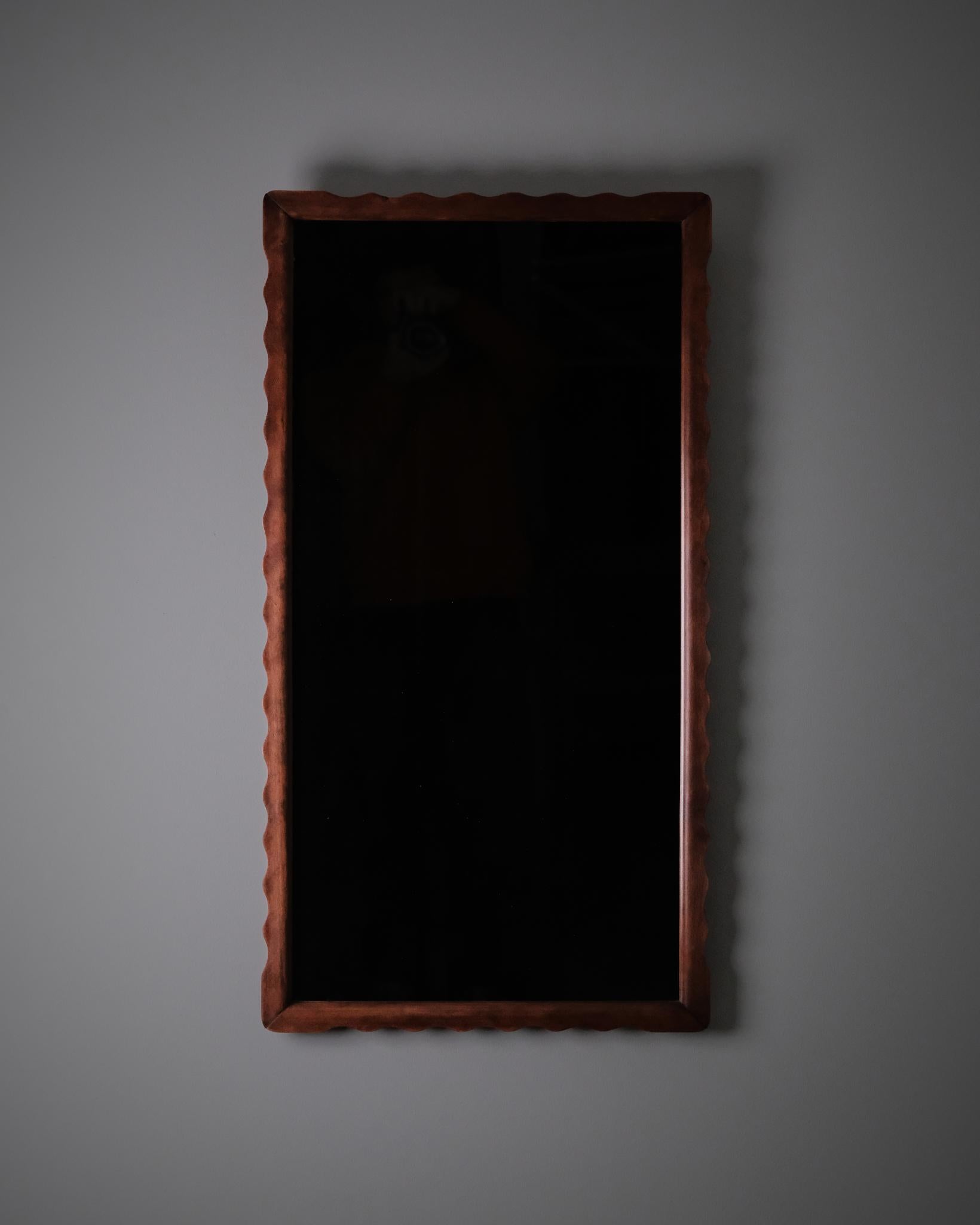 Elegant miroir mural produit par Fröseke dans les années 1940, illustrant la simplicité raffinée du design moderne suédois. Le cadre est fabriqué en hêtre avec des bords subtilement ondulés, en forme de vagues, qui ajoutent un rythme tactile à sa