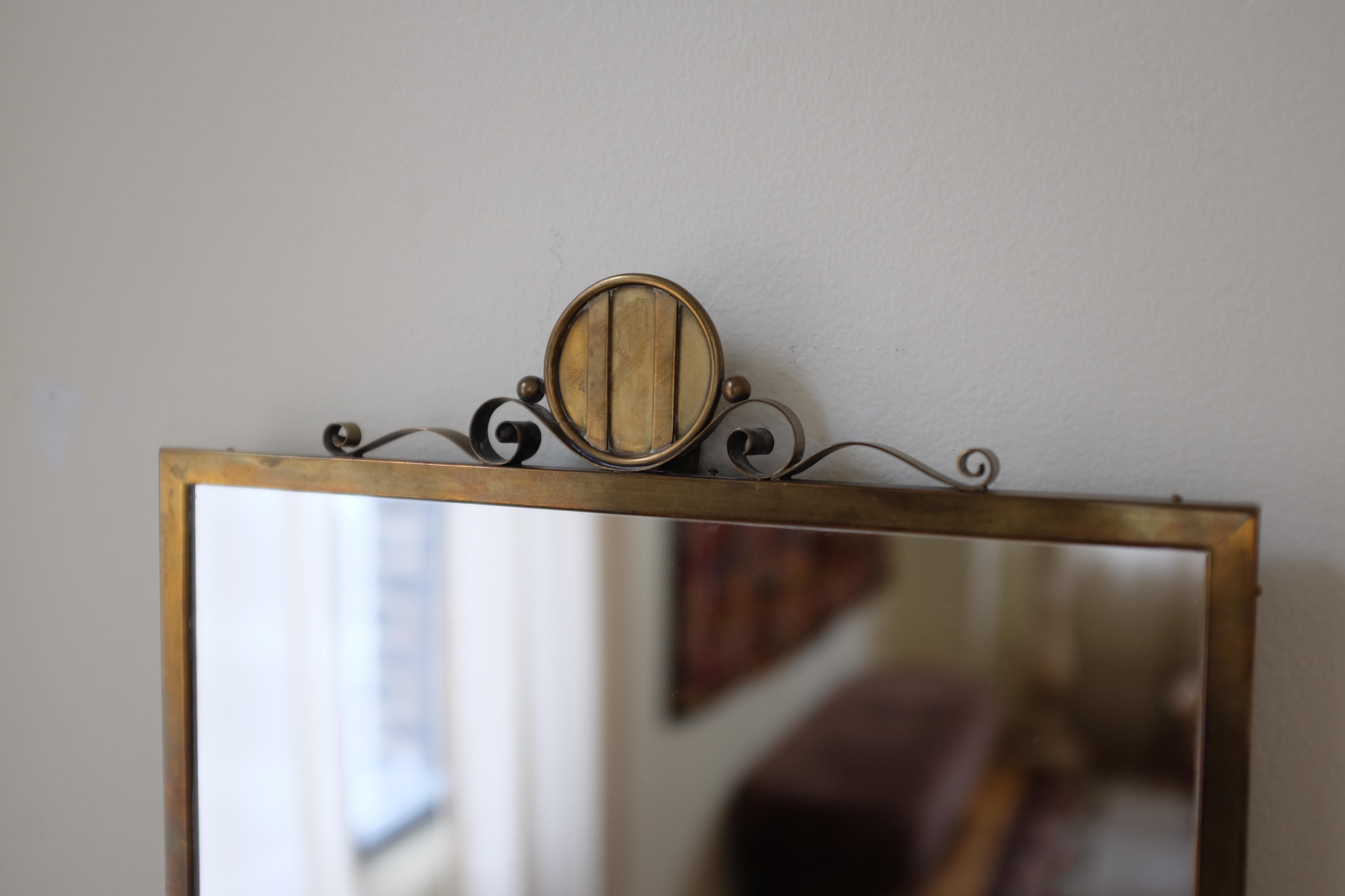 Swedish Modern Metal Wall Mirror circa 1950s. Beautiful organic shaped ornament on the top of the mirror. Very good condition with age appropriate wear to the metal and the glass.

Dimensions: H 18.75 in x W 12.25 in

Seen here on a Cuff Studio