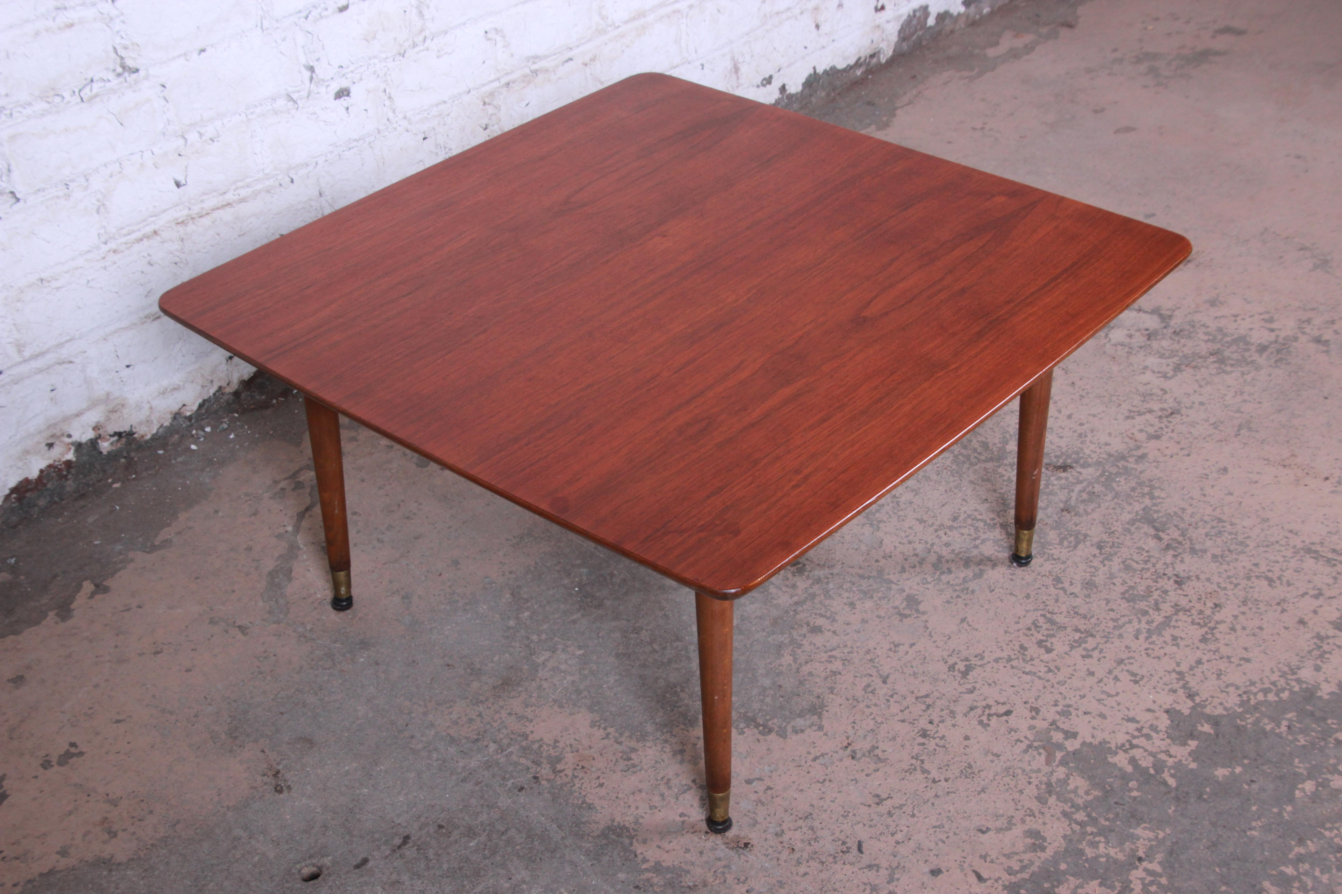 Offering a gorgeous Mid-Century Modern Swedish coffee table attributed to Folke Ohlsson for DUX. The table features beautiful walnut wood grain and sleek Scandinavian design. The table rests on four tall solid walnut brass-tipped pencil legs. Marked