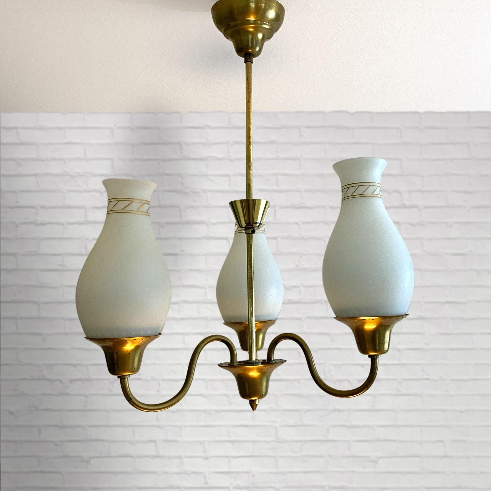 Swedish 1940s pendant lamp made from brass with three curved arms holding bell-shaped shades in opal glass with a decorative golden pattern. The small brass bowl placed on the stem reflects the light in all directions. With its minimalistic shape