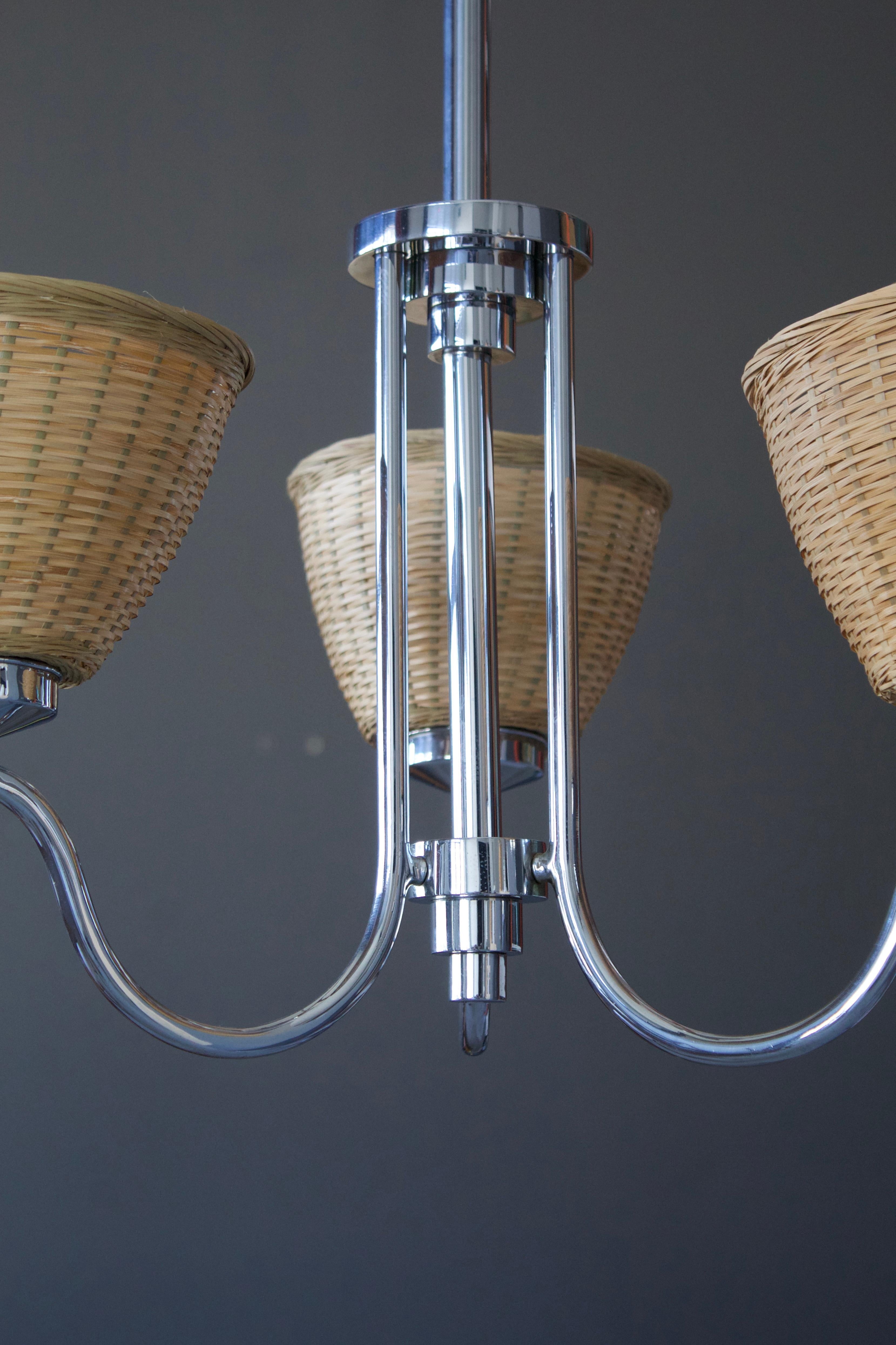 A chandelier light. Designed and produced in Sweden, 1940s. Chome metal, paired with assorted vintage rattan lampshades.