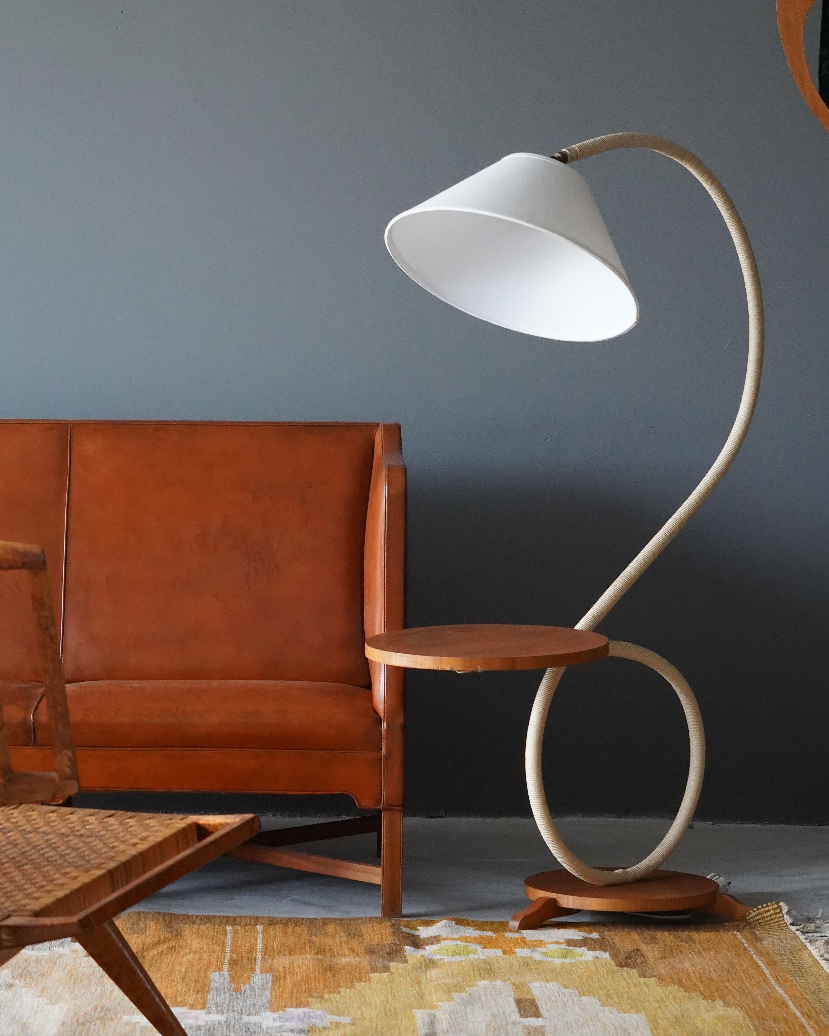A sizable organic floor lamp. Designed by an unknown designer, Sweden, 1940s. Features an interesting mixture of cord wrapped stem on a solid wood base. Brass details. Original mounted side table. Brand new lampshade.

Other designers working in