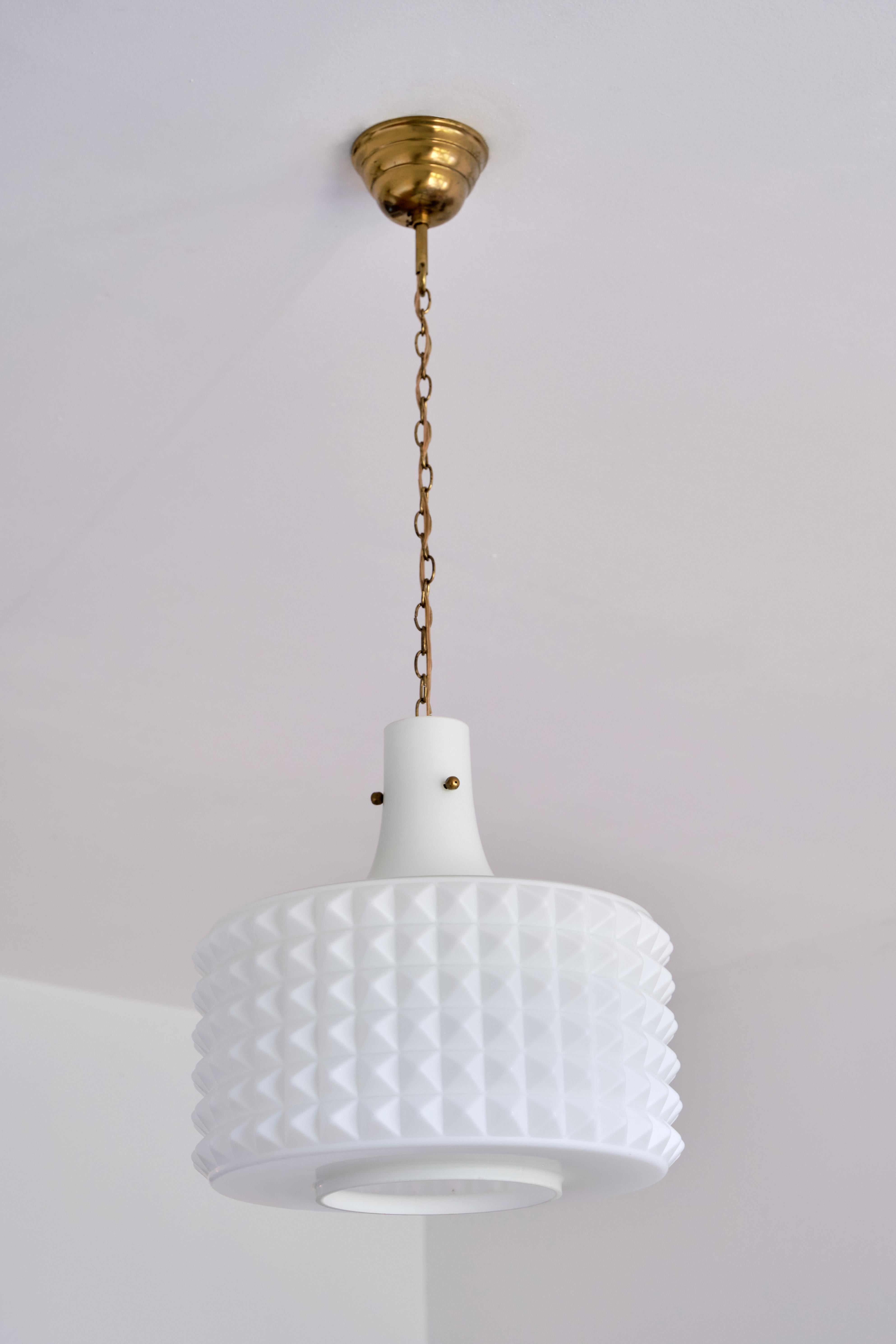 This sculptural modernist pendant lamp was produced in Orrefors, Sweden in the 1950s. The shade is made of a matte white opaline glass. The three-dimensional studded pattern in the glass gives the shade a beautiful and interesting texture, both when
