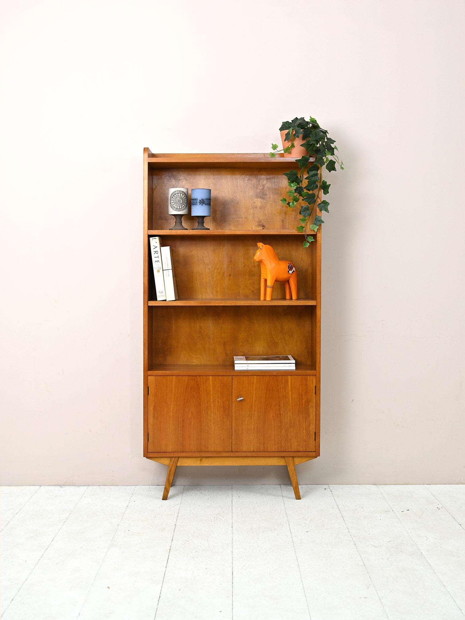 Scandinavian teak bookcase with storage compartment.

An original piece of furniture from the 1960s with shelves and hinged doors.
This bookcase is characterized by the storage compartment closed by the doors, which is located in the lower part.