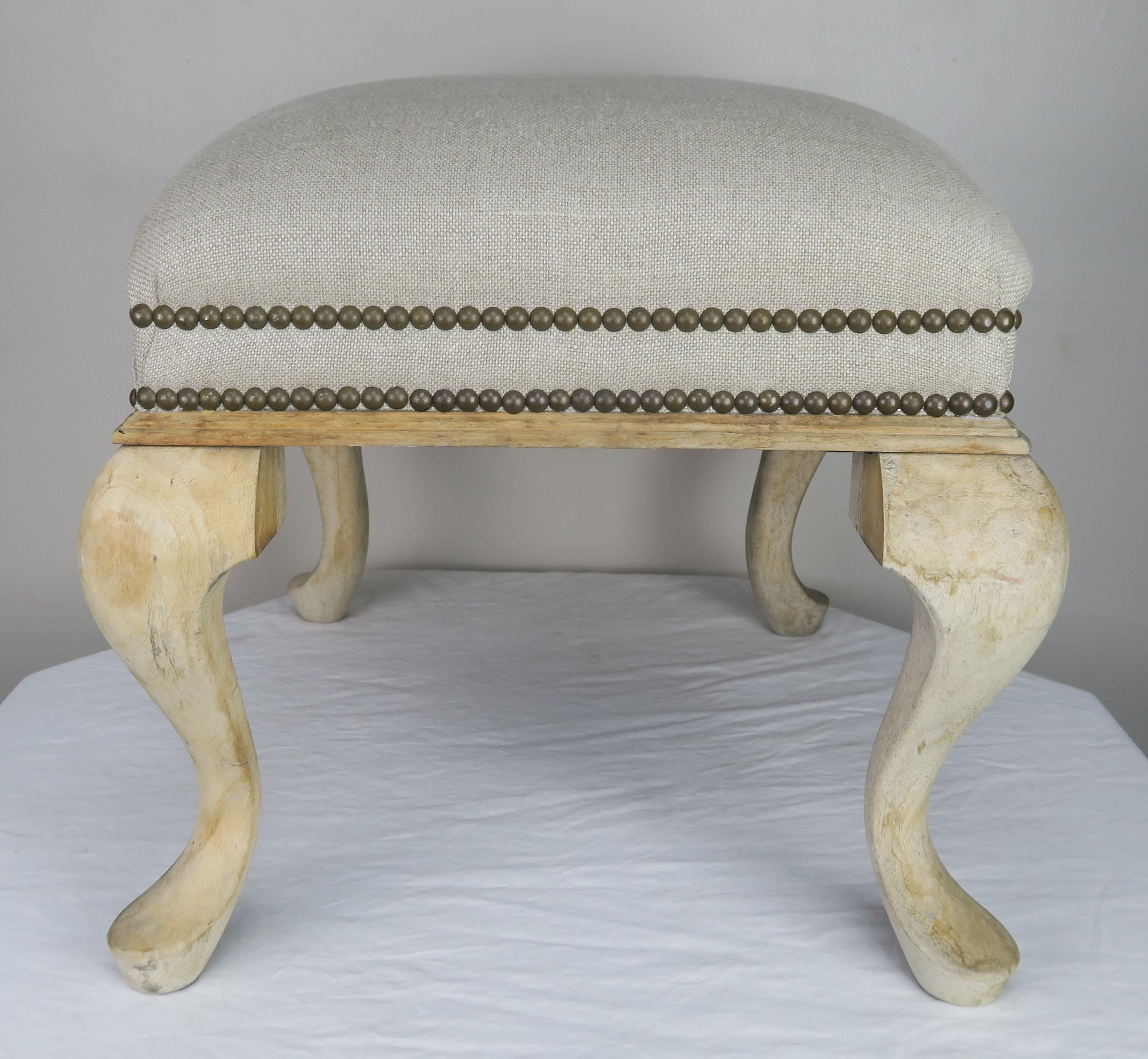 Swedish natural bleached wood bench standing on four legs. The bench is newly upholstered in a washed Belgium linen textiled finished with two rows of antique brass colored nailheads.