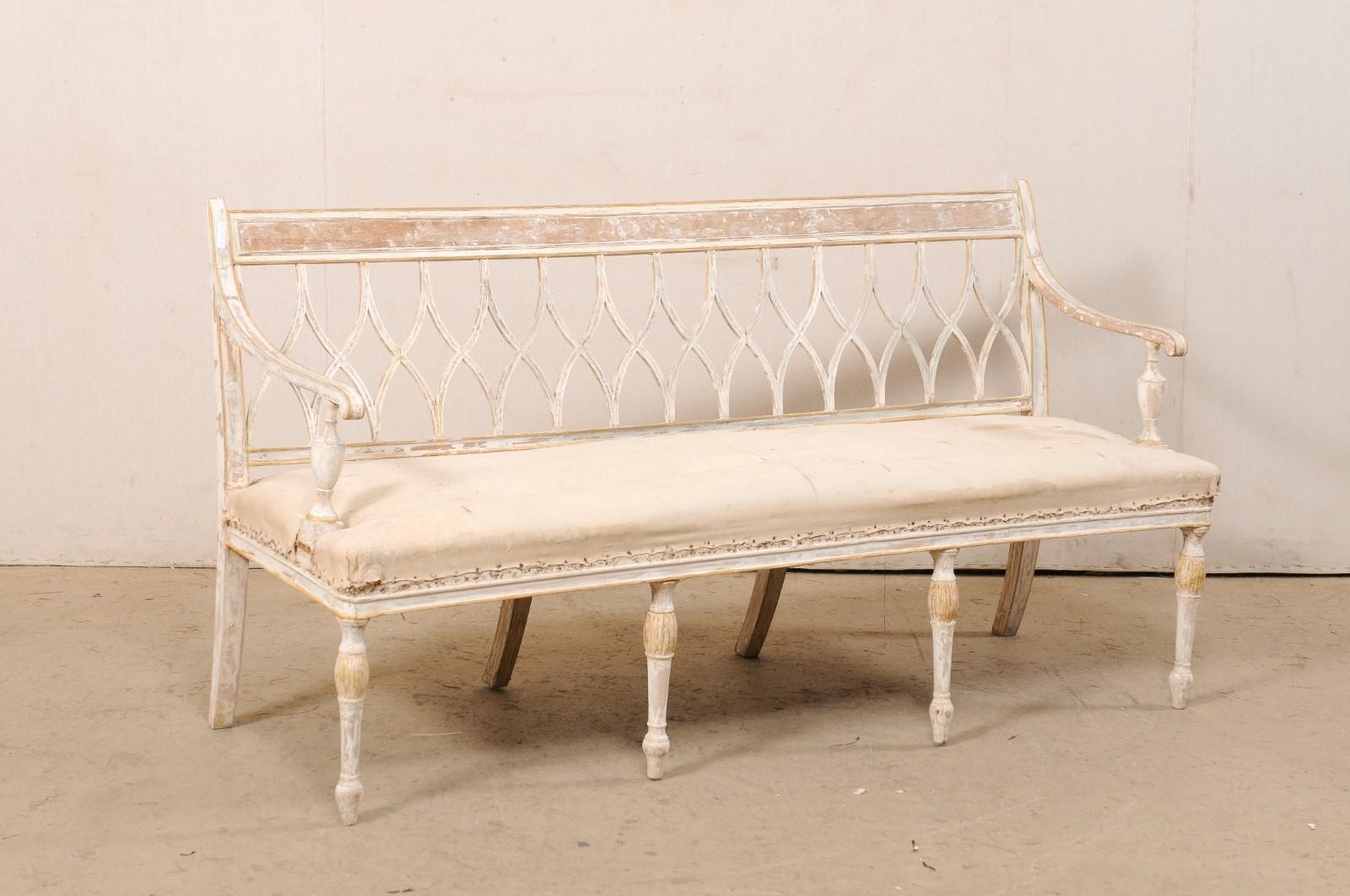 A Swedish Neoclassical style carved-wood sofa bench from the early 19th century. This antique settee from Sweden features a straight back rail atop a beautiful succession of open back splats in curvy x-shaped design (reminiscent of an hour-glass).