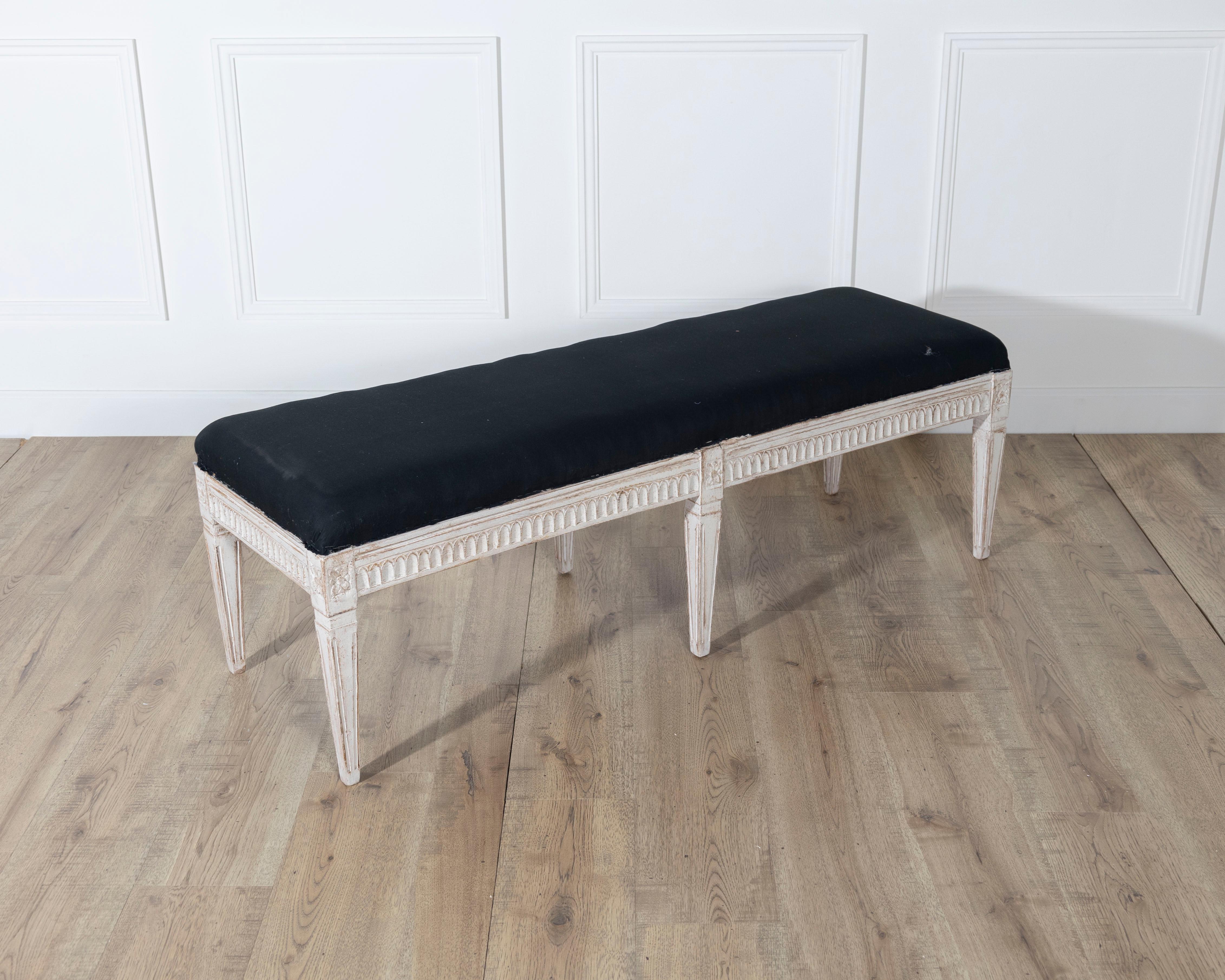 Un banc suédois raffiné du XIXe siècle, incarnant l'élégance du design néoclassique. Le cadre en bois sculpté conserve des traces de sa finition peinte d'origine, aujourd'hui vieillie dans une patine douce qui met en valeur les détails précis. Le