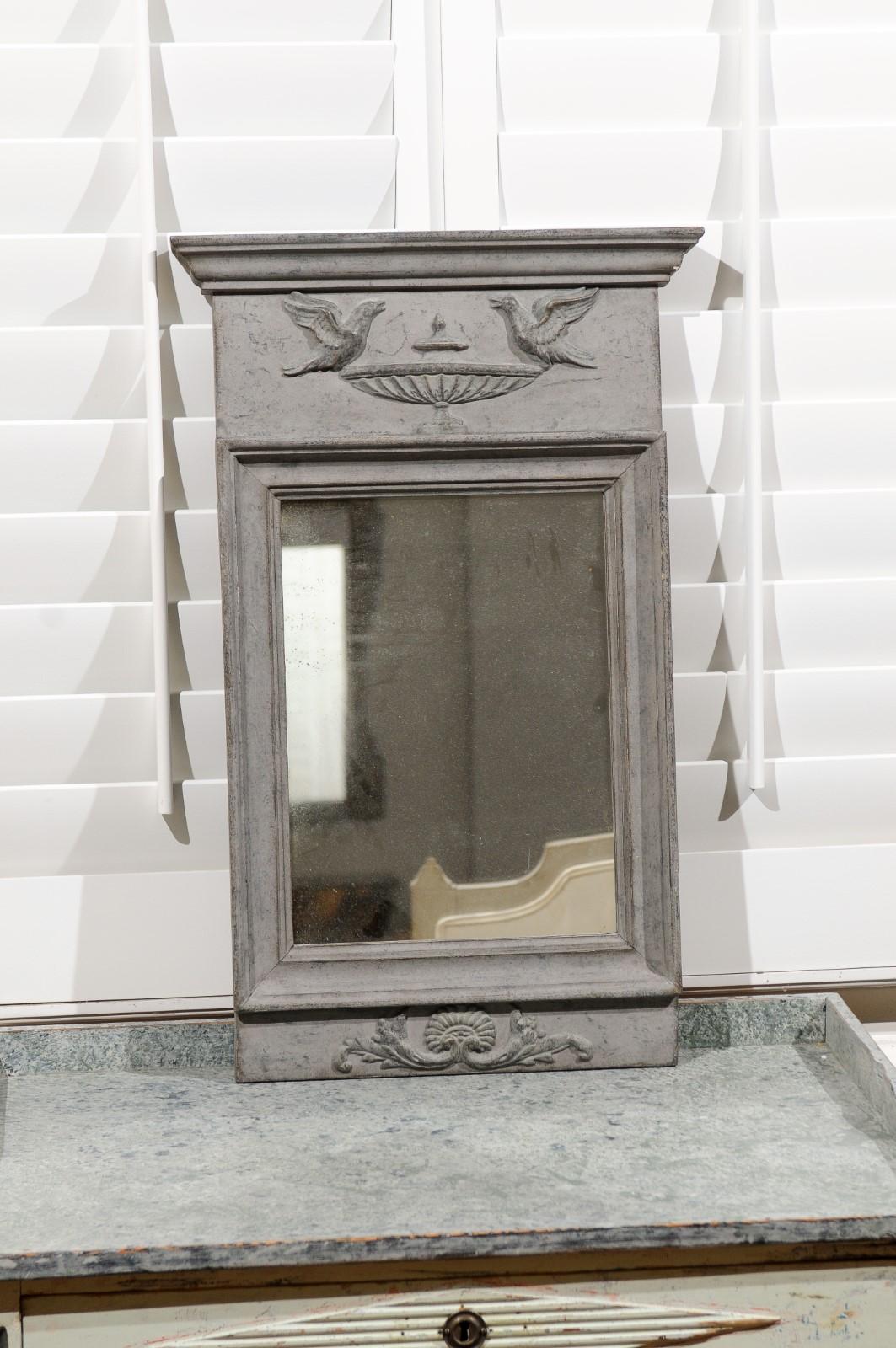 A Swedish neoclassical style painted and carved wooden mirror from the 19th century, with doves on an urn motif. Created in Sweden during the 19th century, this neoclassical style painted mirror features a linear silhouette perfectly adorned with
