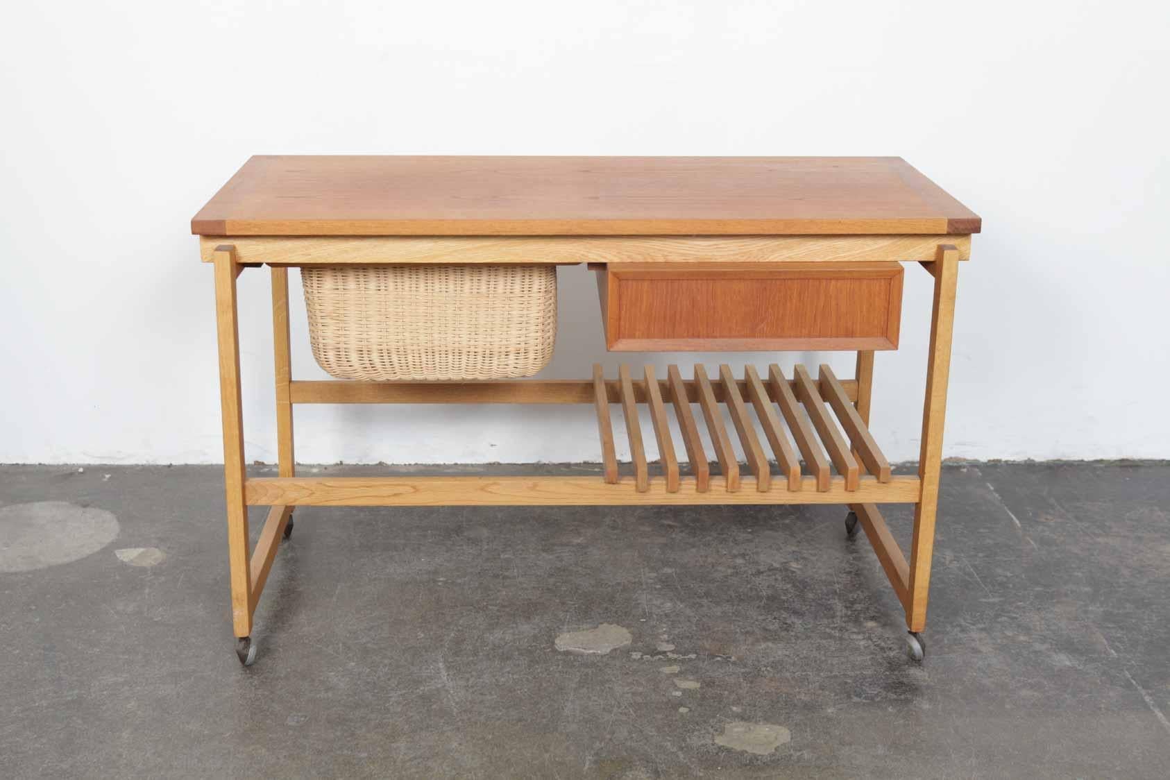 Very unique teak and oak rolling sewing table with cane basket, Sweden, circa 1960. Punctuated by a single drawer and slat style lower shelf, it can easily be used as a drinks trolley as well. Solid construction, it has been newly refinished in a