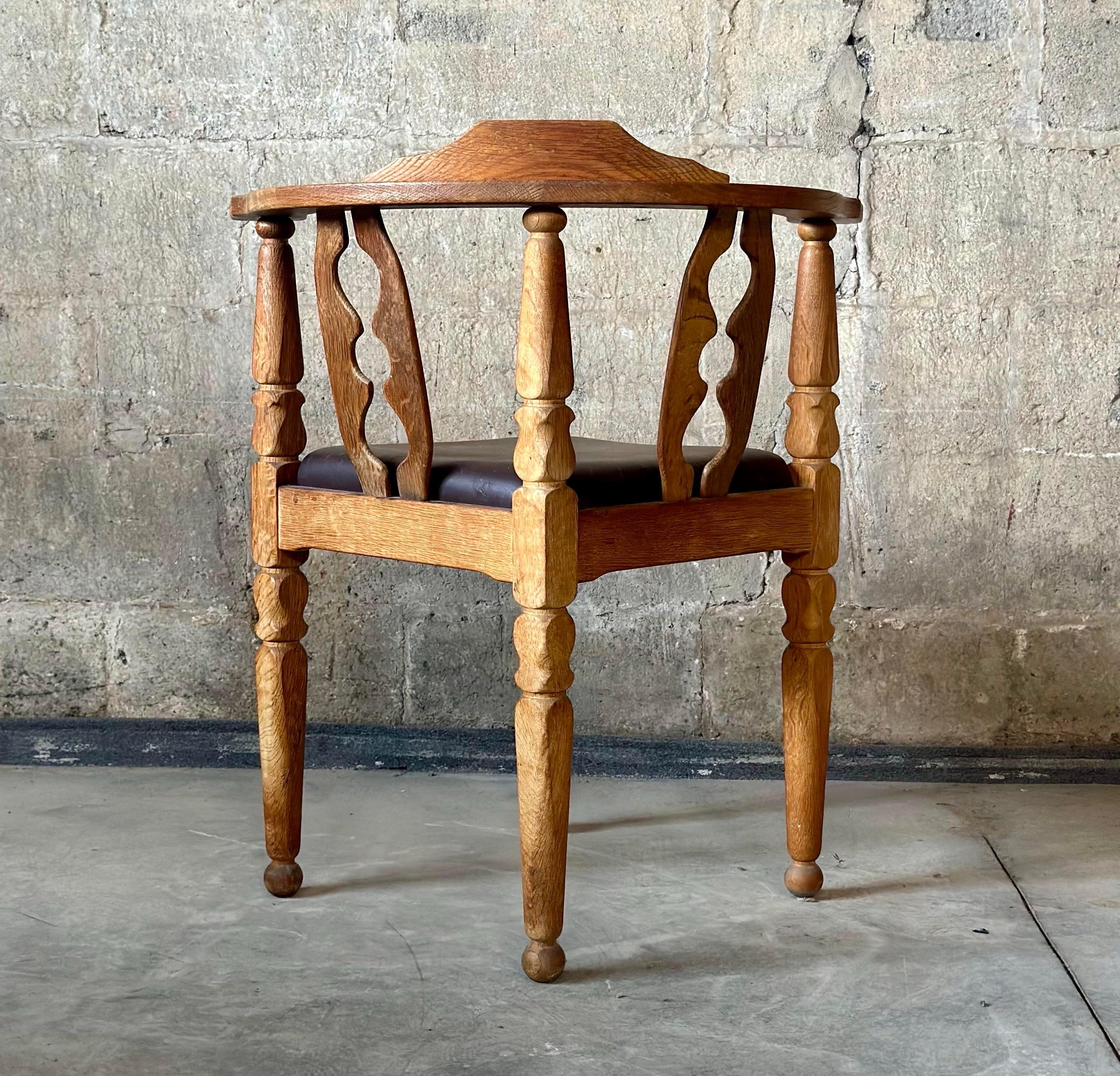 A charming Swedish corner chair in quarter-sawn oak. The curve of the seat back, mirrored in circular pierced back splats, contrasts with the square seat upholstered in delicious chocolate brown colored leather.