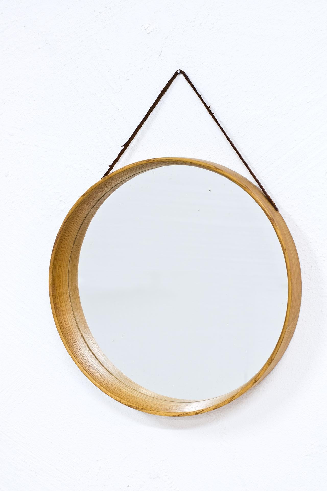 Midcentury round wall mirror manufactured in Sweden. Made from oak with leather strap.