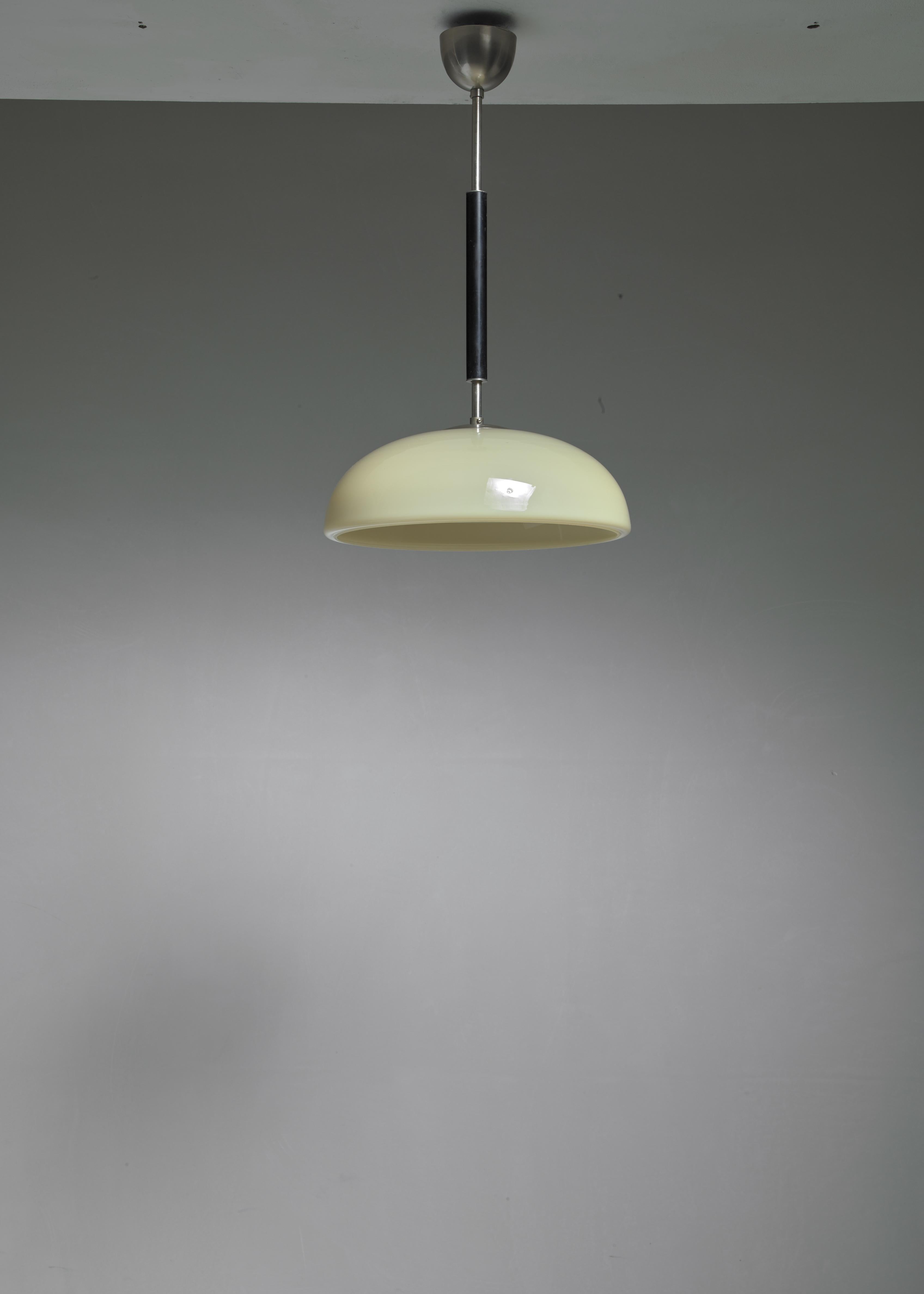 A 1920s Swedish modernist pendant made of a yellow glass shade with an opaline glass diffuser and a nickel with bakelite stem.