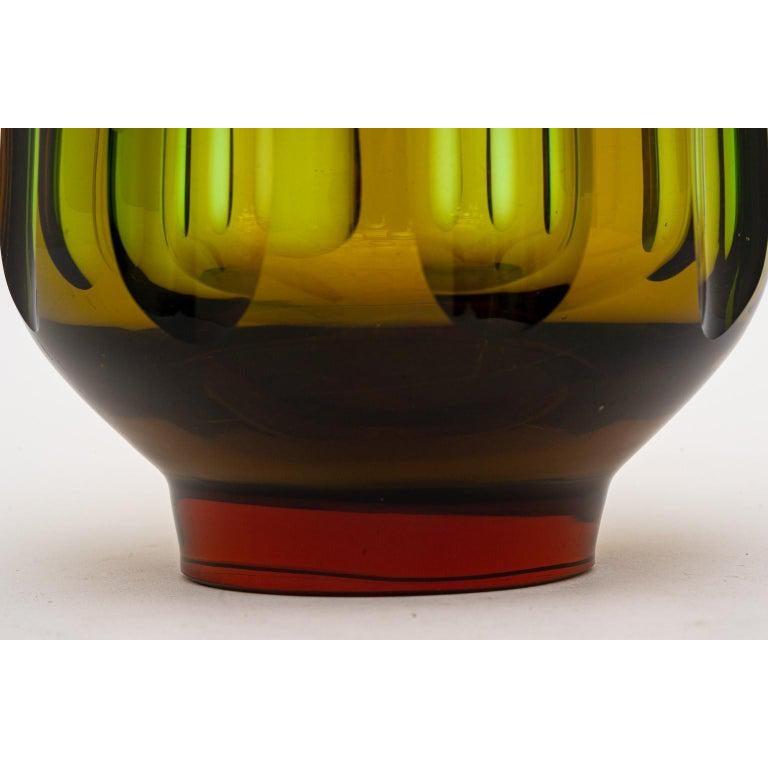 This stylish Swedish glass vase dates to the 1960s-1970s and has an elongated optic pattern in colors of smokey bronze-green.