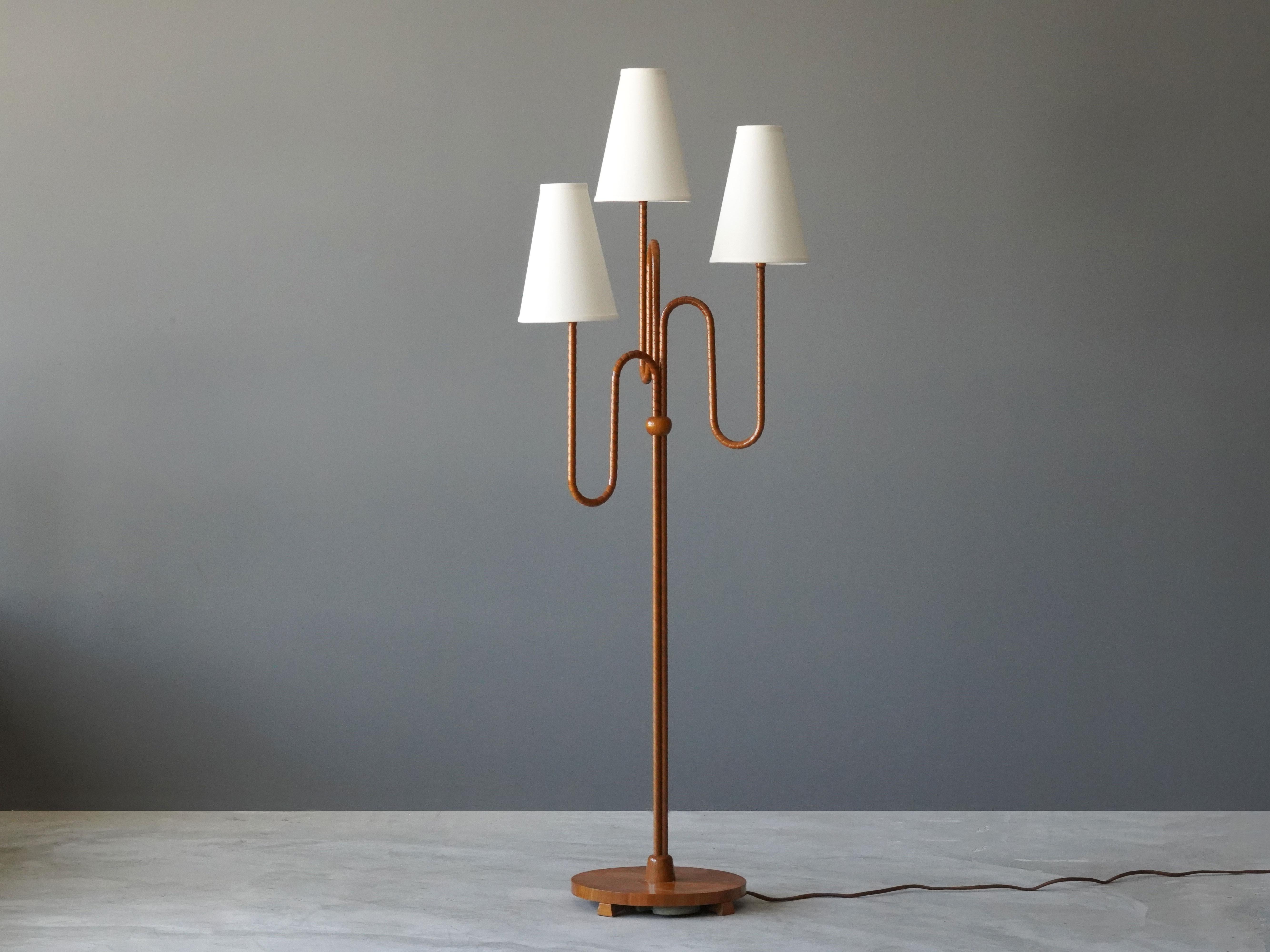 An organic three-armed floor lamp. Designed by an unknown Swedish modernist designer, 1930s. Possibly manufactured by Böhlmarks. Produced in rattan, wood, linen, and brass. 

Other designers working in the organic style include Jean Royere, Gio