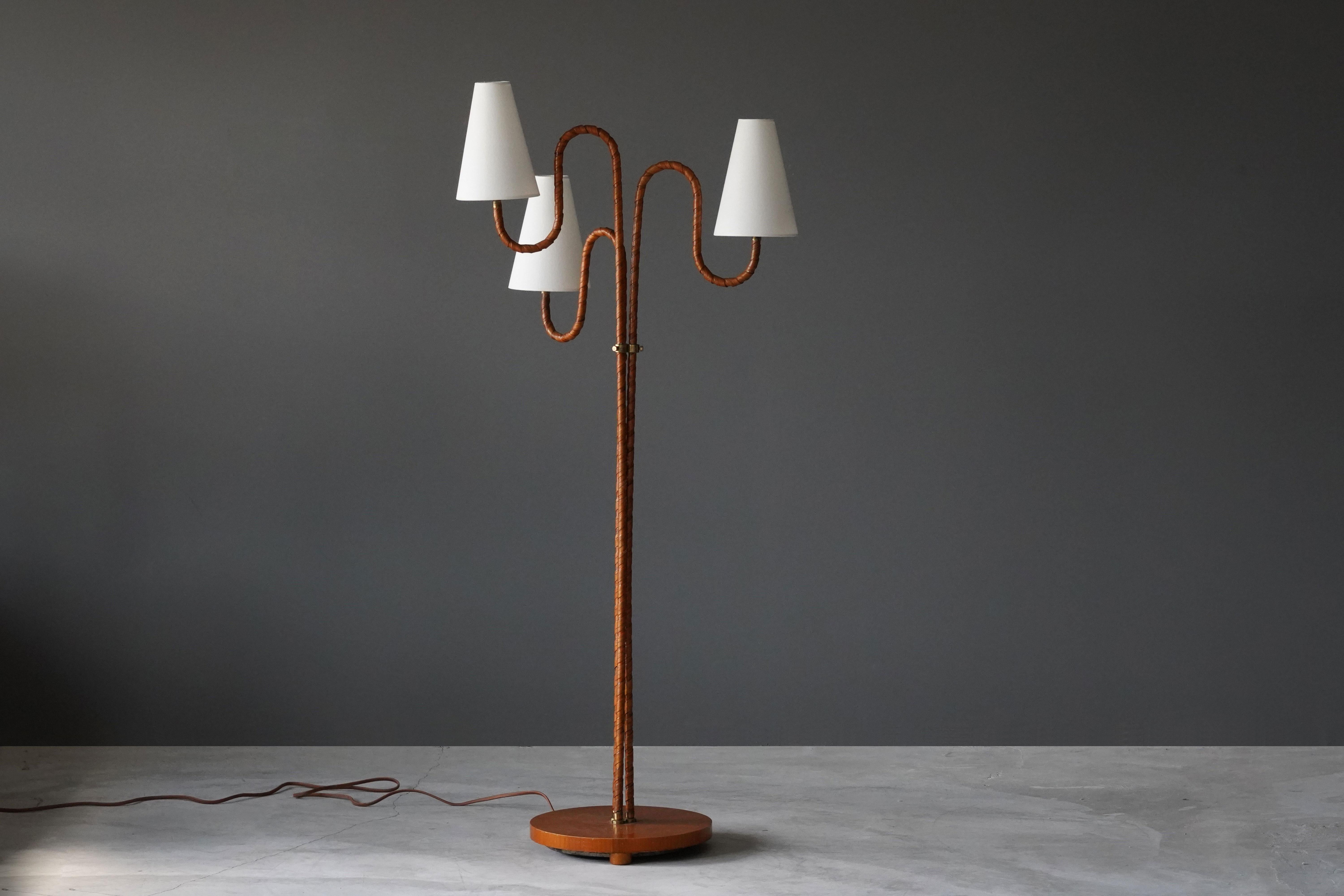 An organic three-armed floor lamp. Designed by an unknown Swedish modernist designer, 1930s. Possibly manufactured by Böhlmarks. Produced in rattan, wood, linen, and brass. Arms adjustable. 

Other designers working in the organic style include